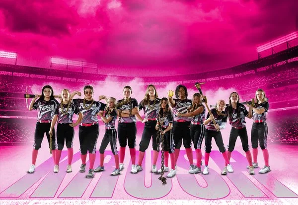Women's fastpitch softball team posing on field with pink sky background