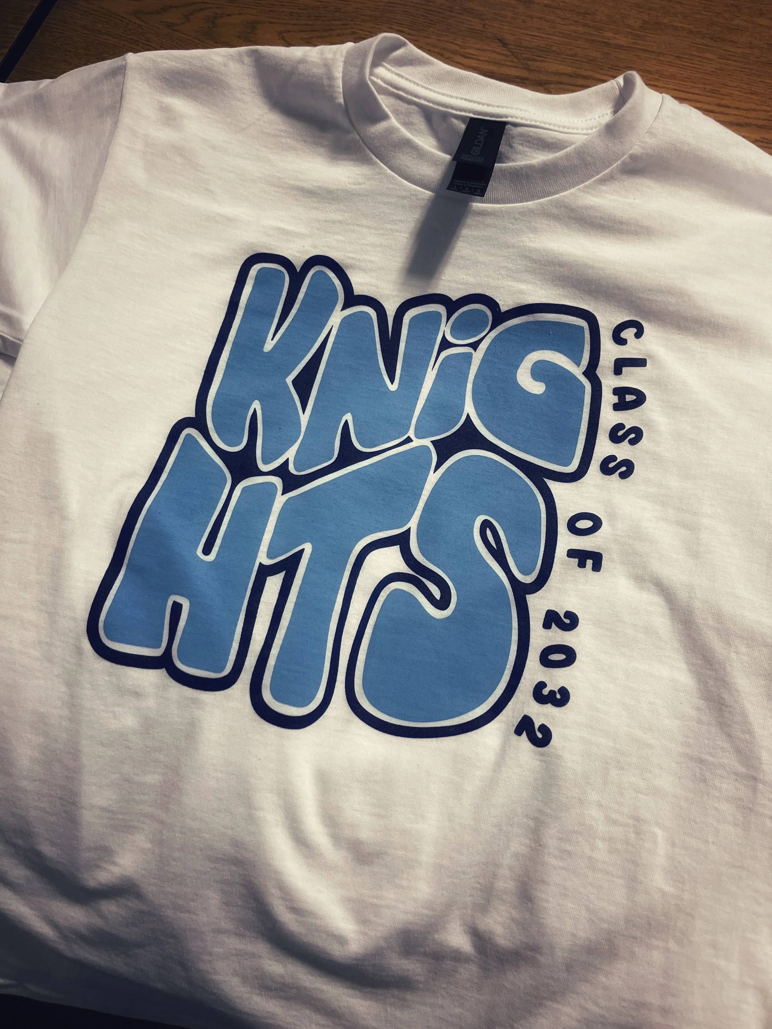 White T-shirt with blue and black graphics and printed numbers.