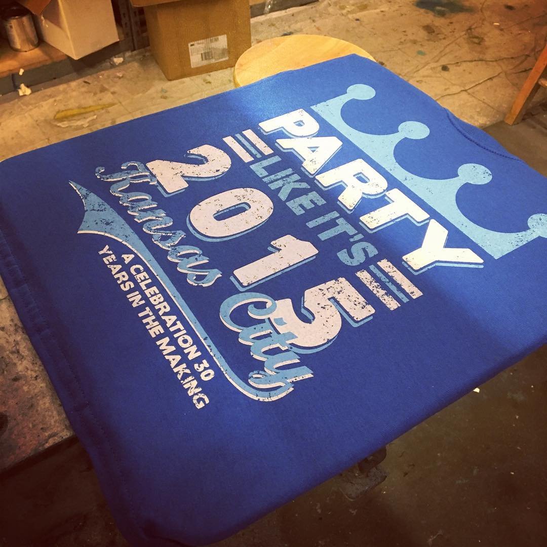 Blue T-shirt with a vintage-style circular graphic and lettering.