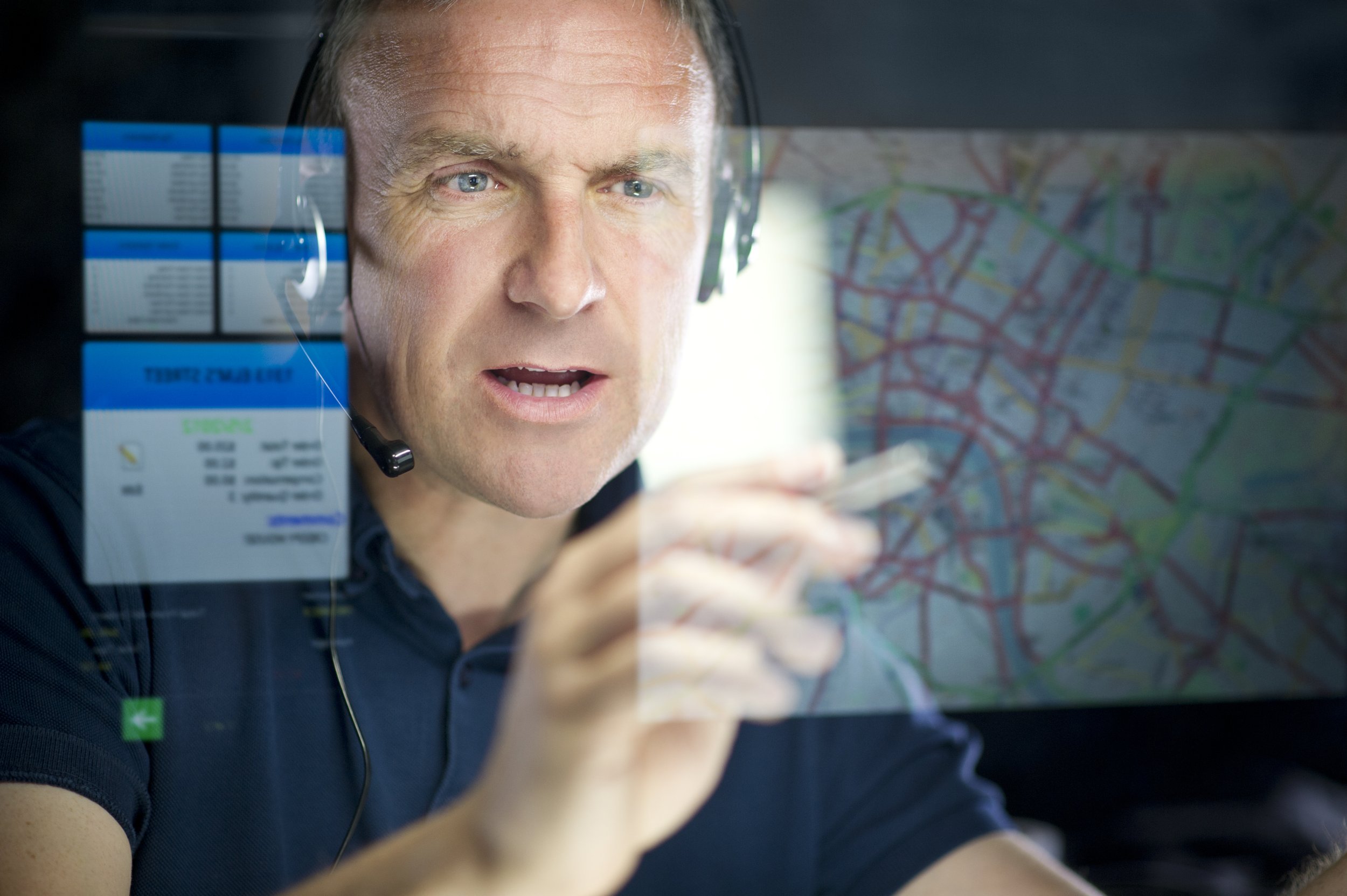 man seen through transparent disply pointing at map