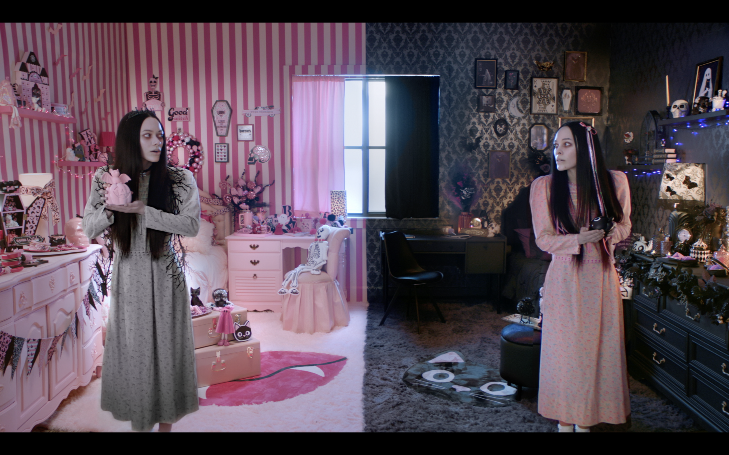 Room split into pink-themed and dark-themed sides. Two women in pajamas, one holding a pink pig plush, the other holding a camera, stand in their respective sides amid decorated rooms with various accessories.