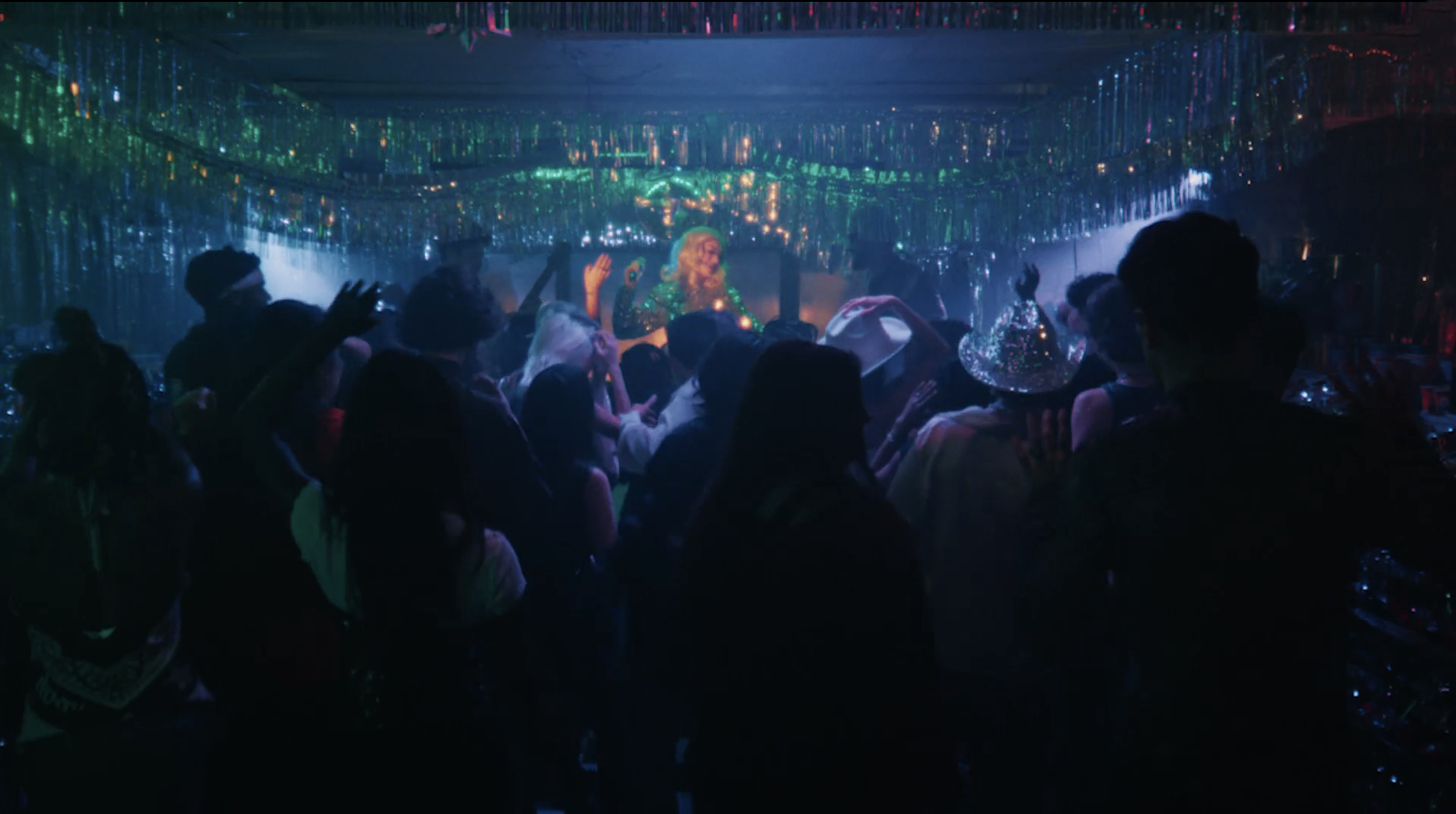 People dancing and celebrating at a party with colorful lights and decorations.
