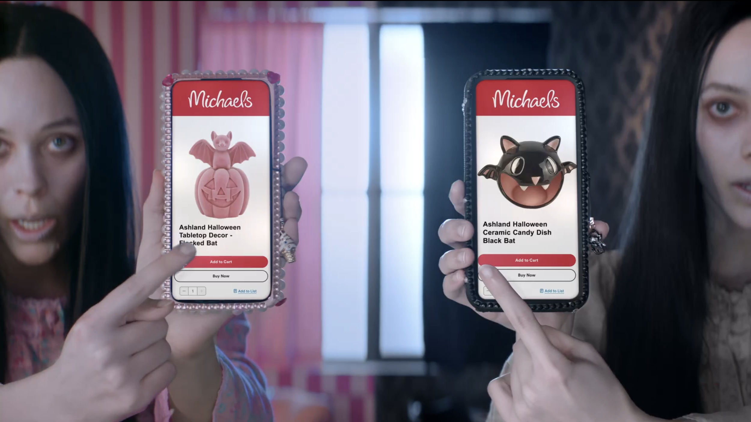 Two women holding smartphones displaying Halloween-themed toy products from Michaels, including a pink bat figure on a pumpkin and a black bat figure on a ceramic dish.
