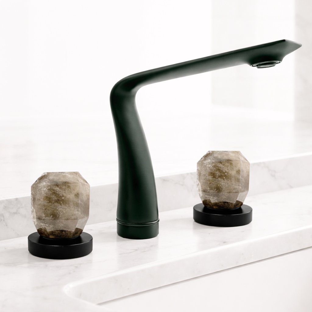 Black kitchen faucet over a white marble countertop with two decorative salt lamps on black bases.