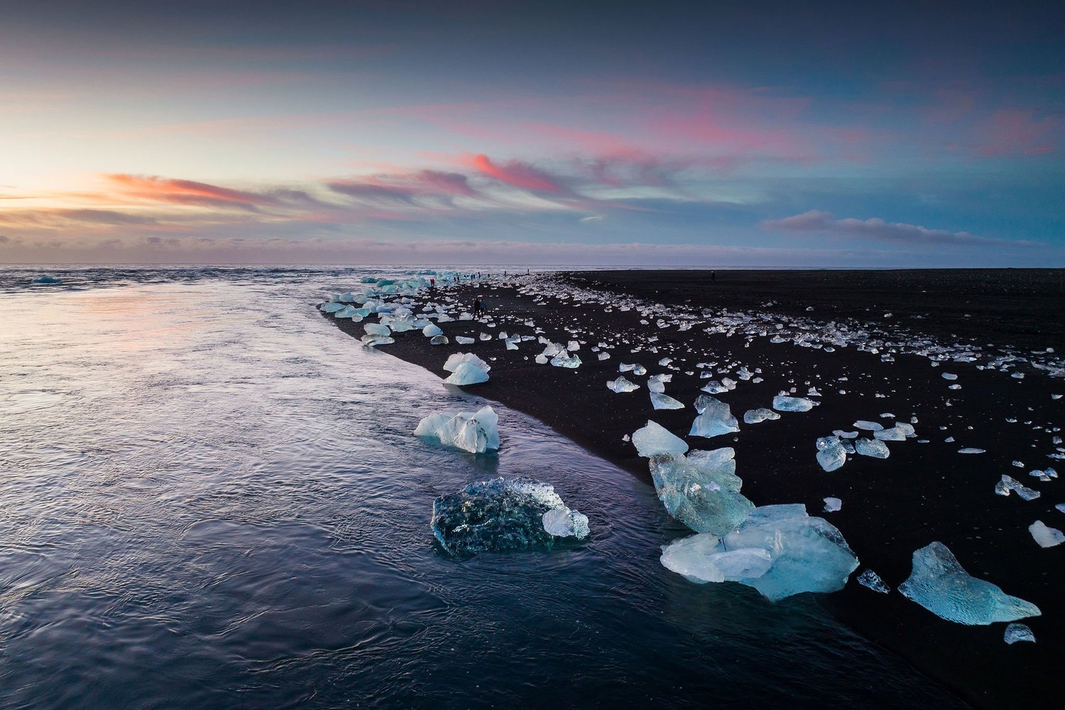A colourful sunset over the ocean and black sand at Diamond Beach