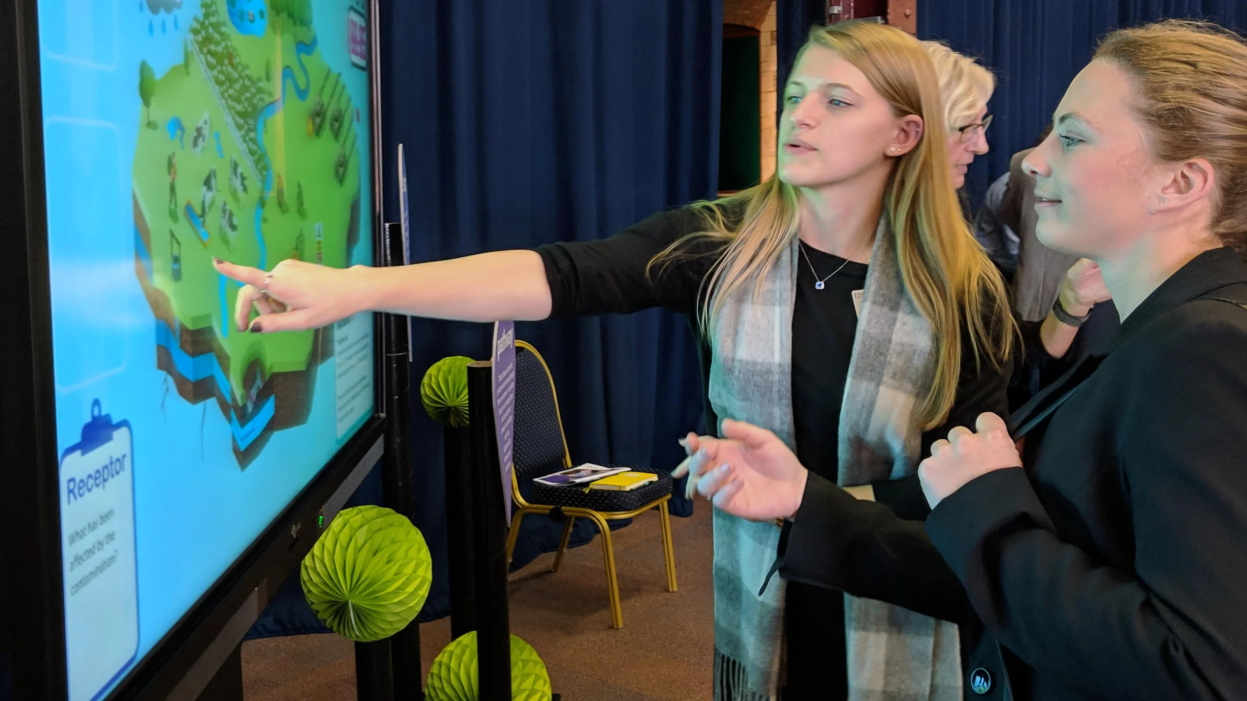 Students interact with the Contamination Challenge Game on a CTOUCH interactive touchscreen at the Defence and Security Doctoral Symposium (DSDS).