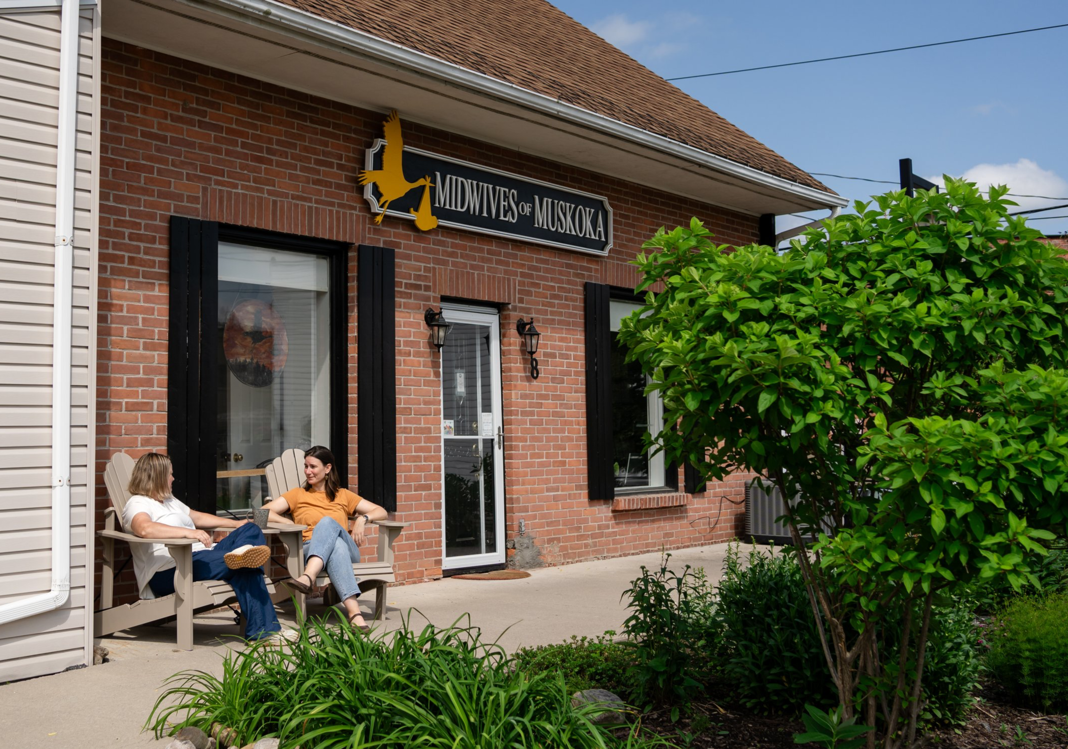 A man and young boy smiling and posing together outside a building, the man wearing a plaid jacket and a cap labeled 'Chad', the boy wearing a colorful dinosaur-patterned outfit and a jacket.