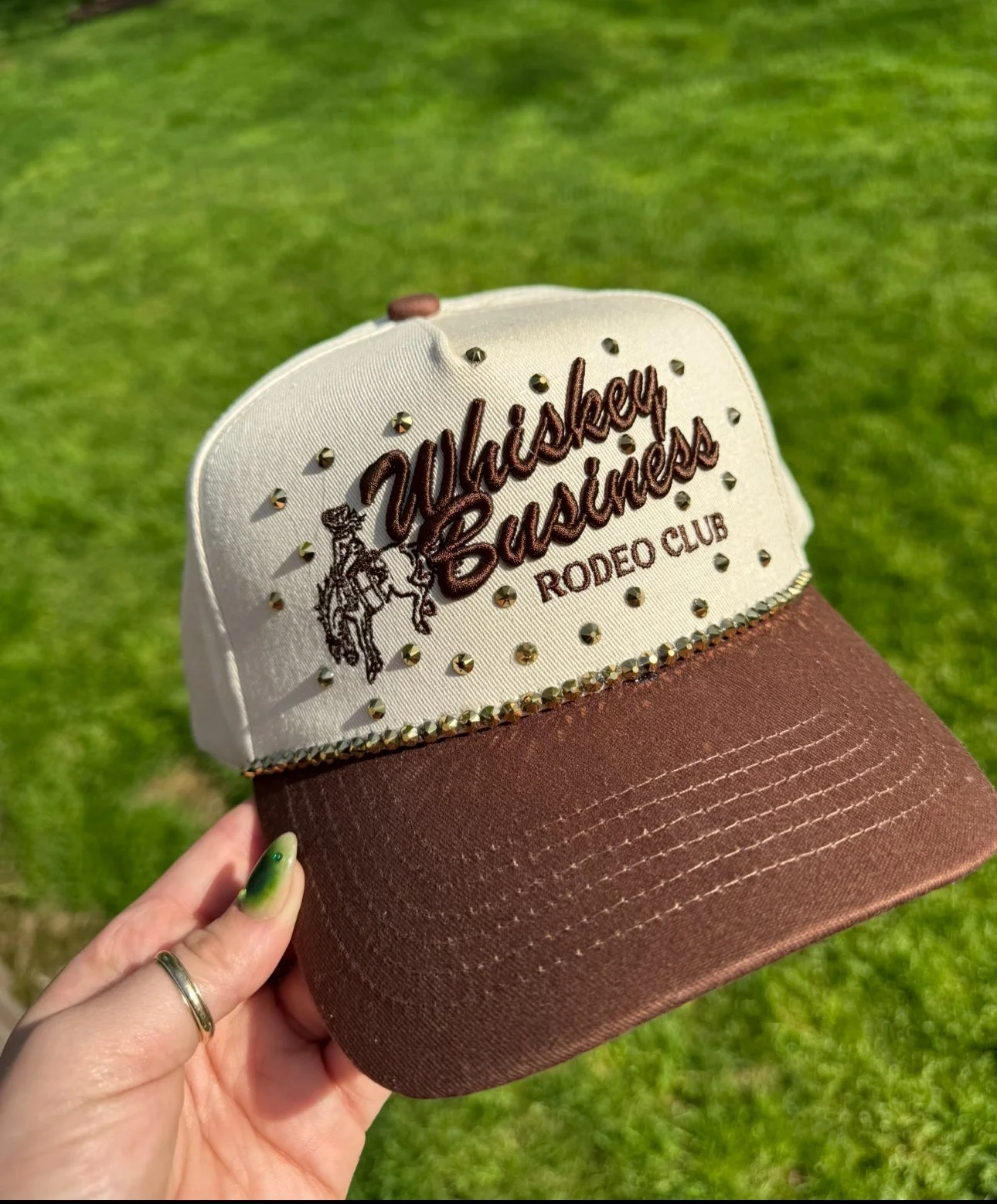 Cap with embroidered text saying 'Whiskey Business Rodeo Club' surrounded by small rhinestones.