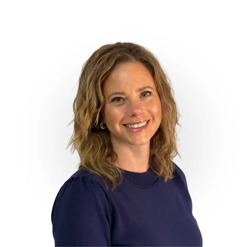 A woman with shoulder-length brown hair, smiling, wearing a navy blue top, against a plain white background.