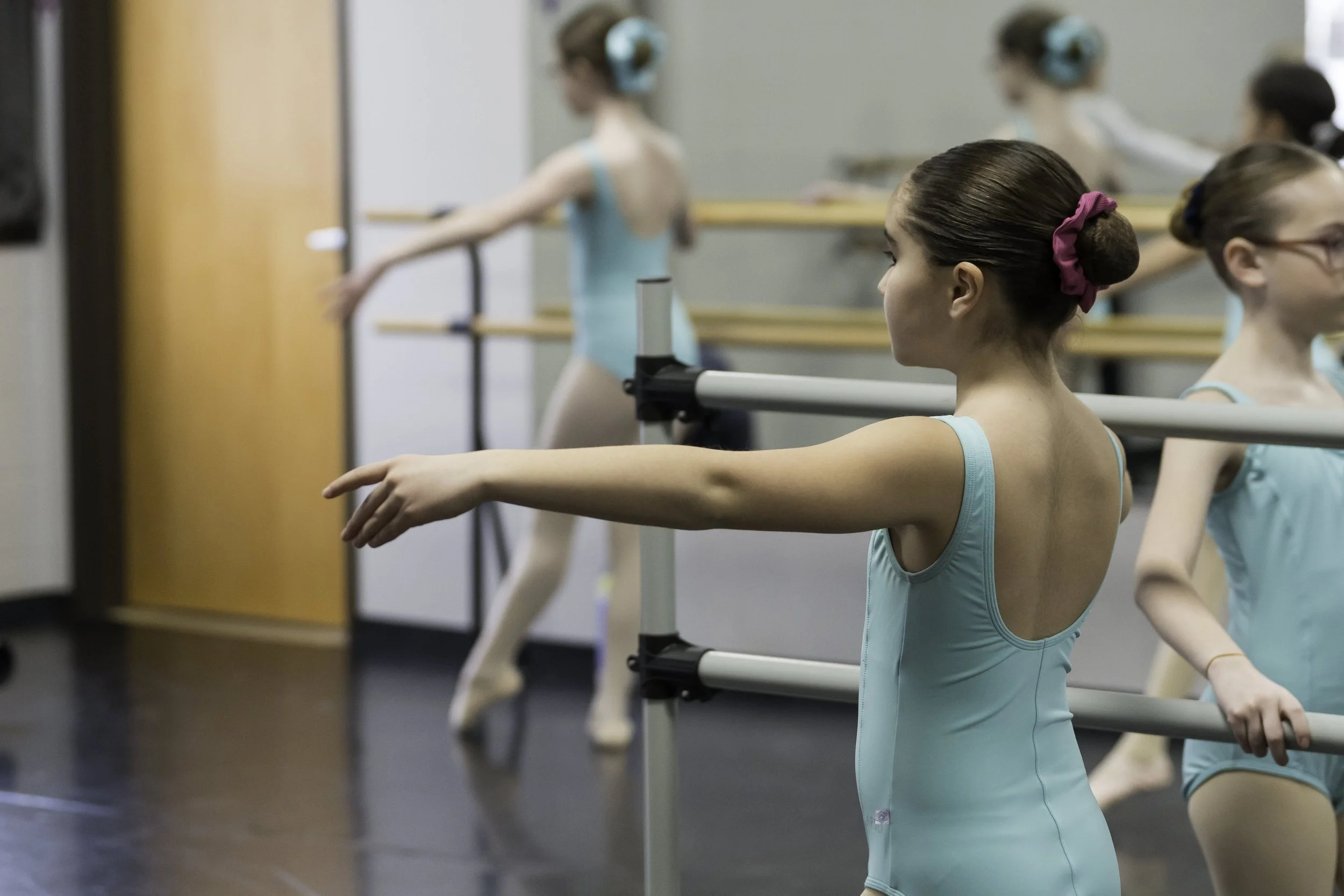 Ballet students at the barre practicing in a dance studio