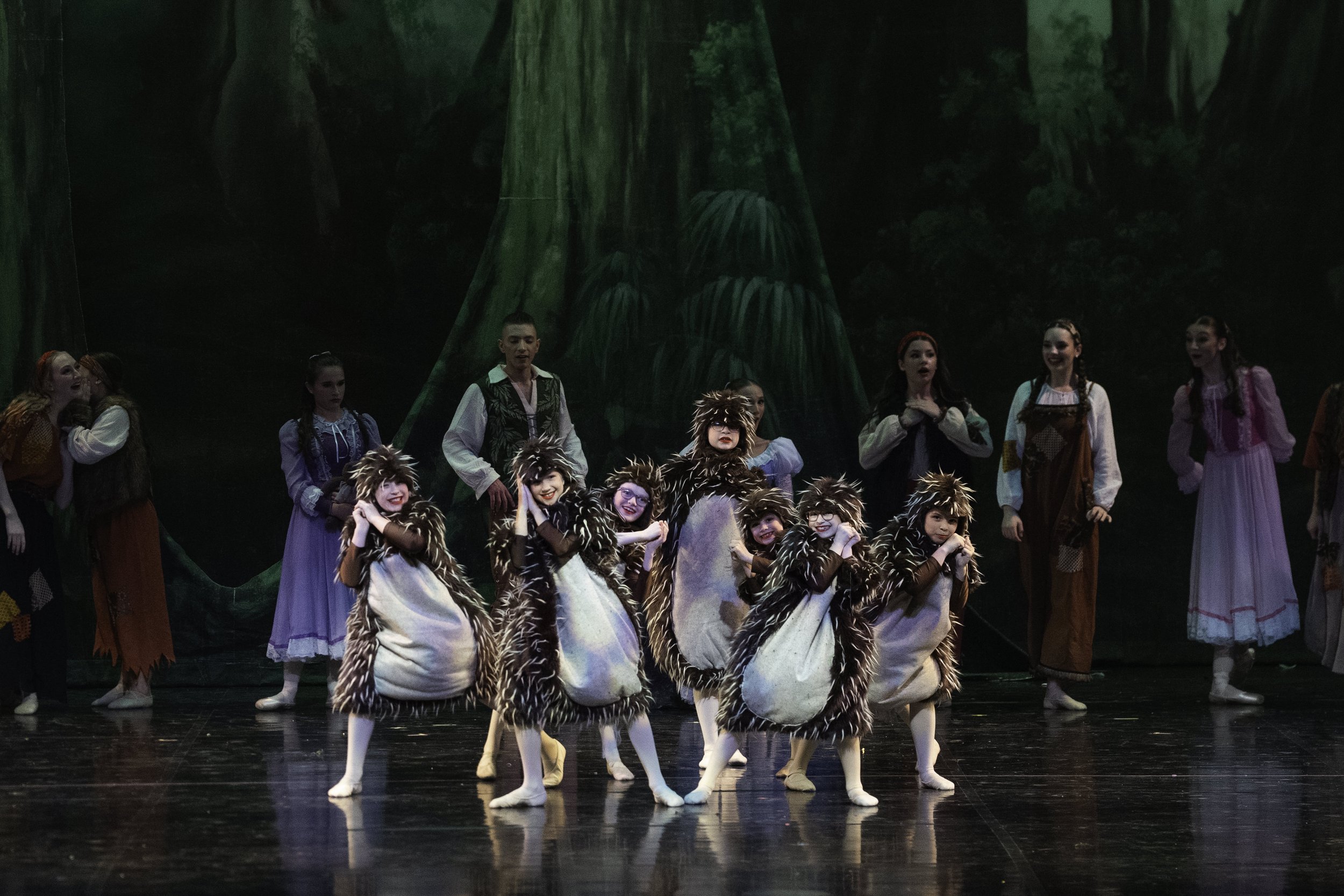 Children dressed as mice performing in a ballet on stage with a forest backdrop.