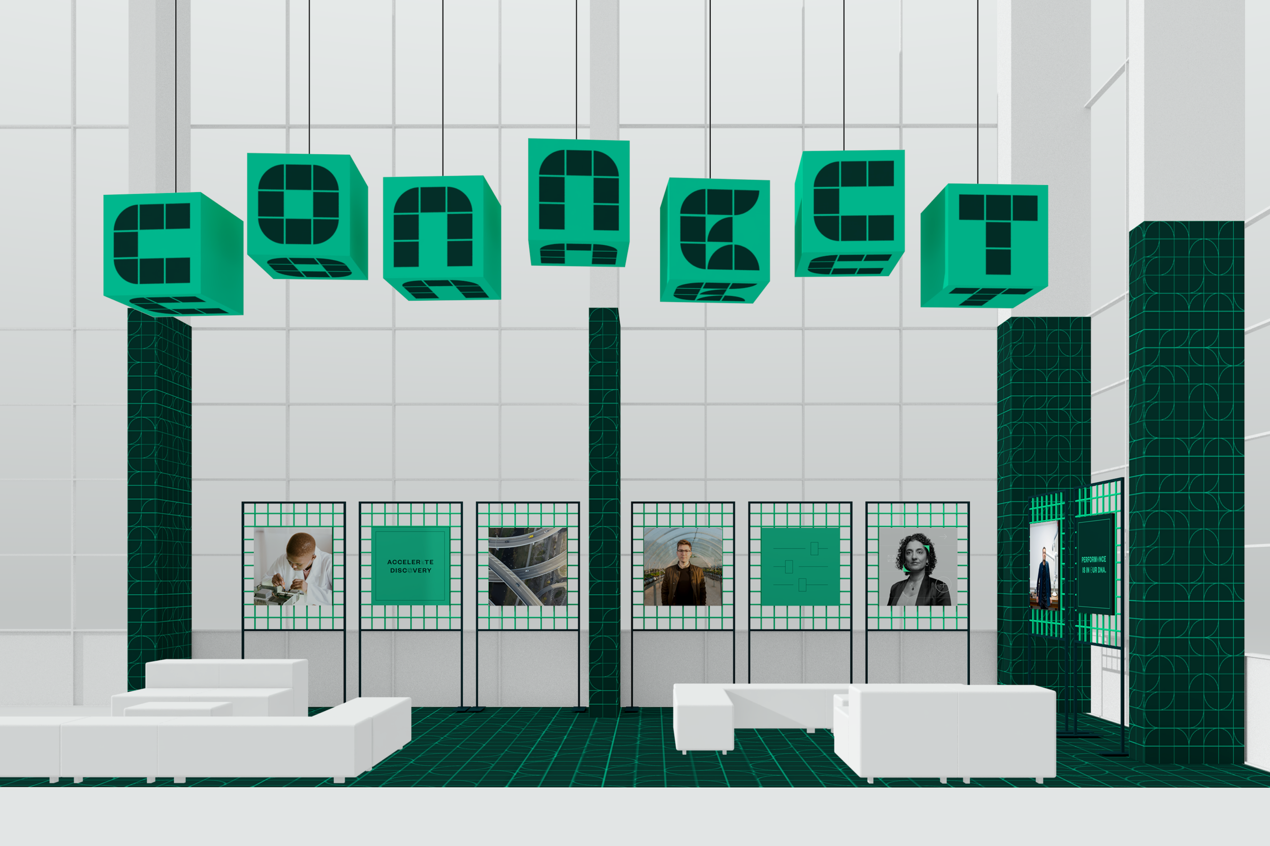 A modern exhibition or presentation space with white walls and black grid flooring, featuring a series of printed graphics on a grid-like backdrop, including a child examining something, the phrase "Accelerate Discovery," a bridge view, a man in business attire, a flowchart, a woman, and a digital display with a person in a suit.