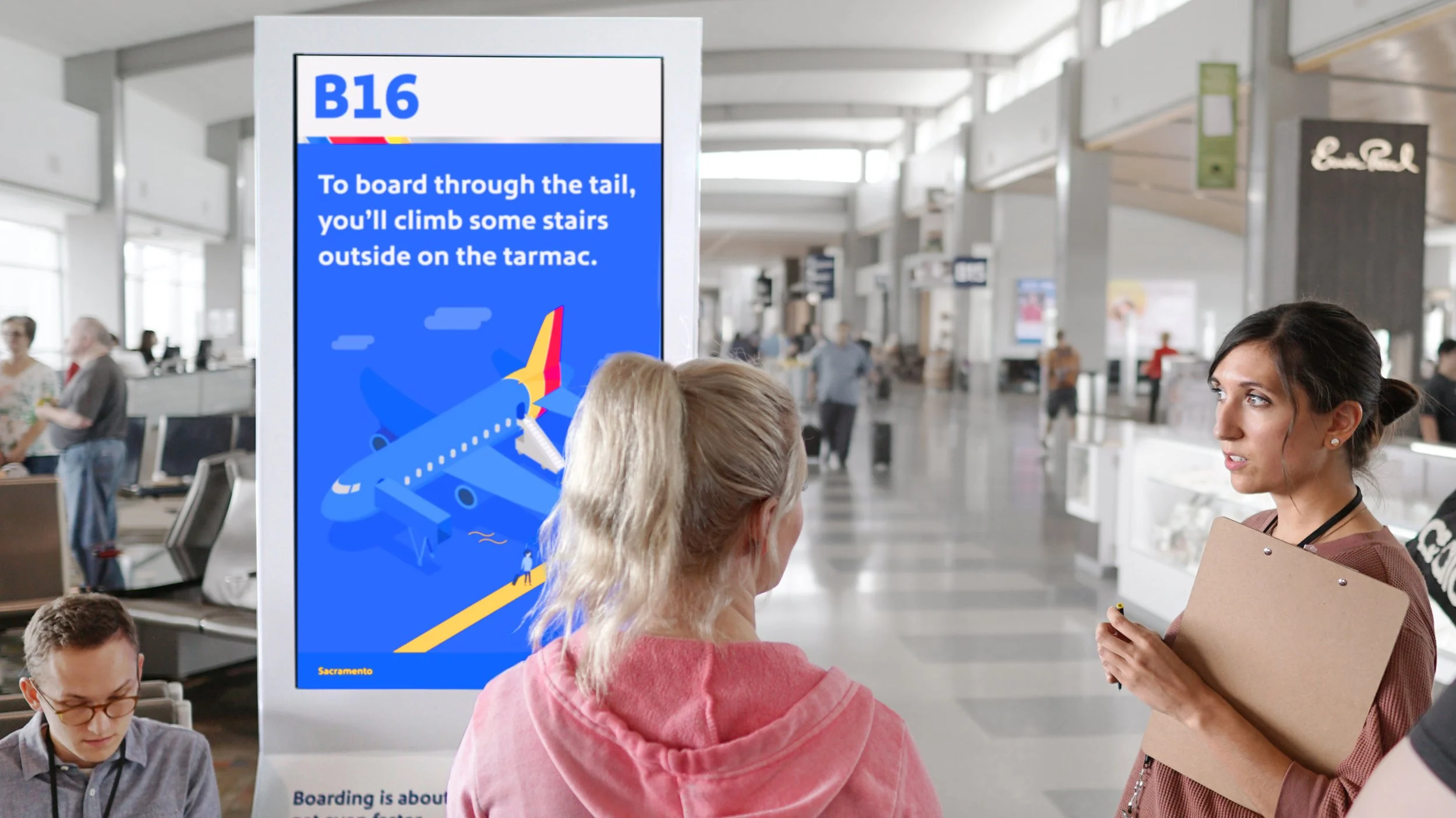 Passengers at an airport check-in area. A woman is talking to a staff member holding a clipboard, while a digital display board shows boarding information for Gate B16 with instructions to board outside on the tarmac.