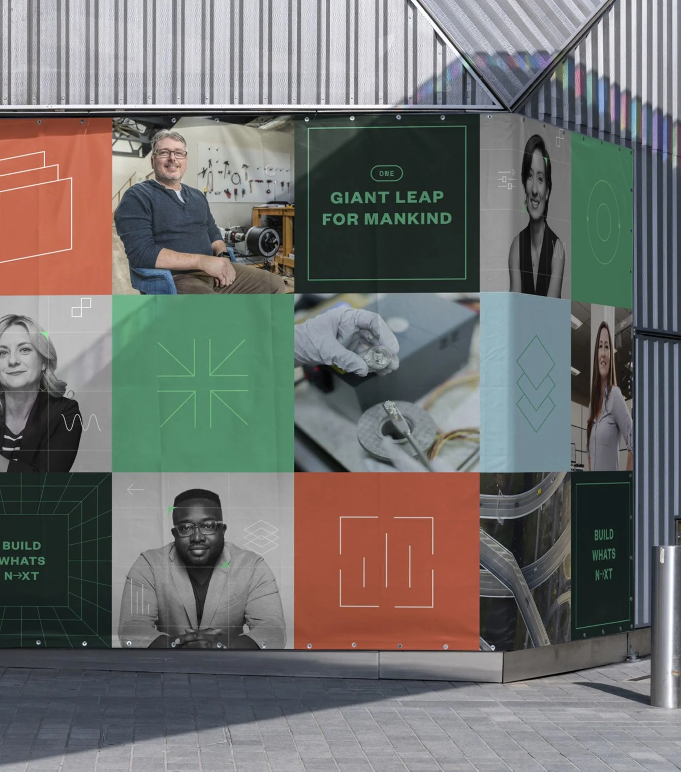 A large, colorful mural on a metal wall featuring various people, scientific and technological images, and the phrase "Giant Leap for Mankind."