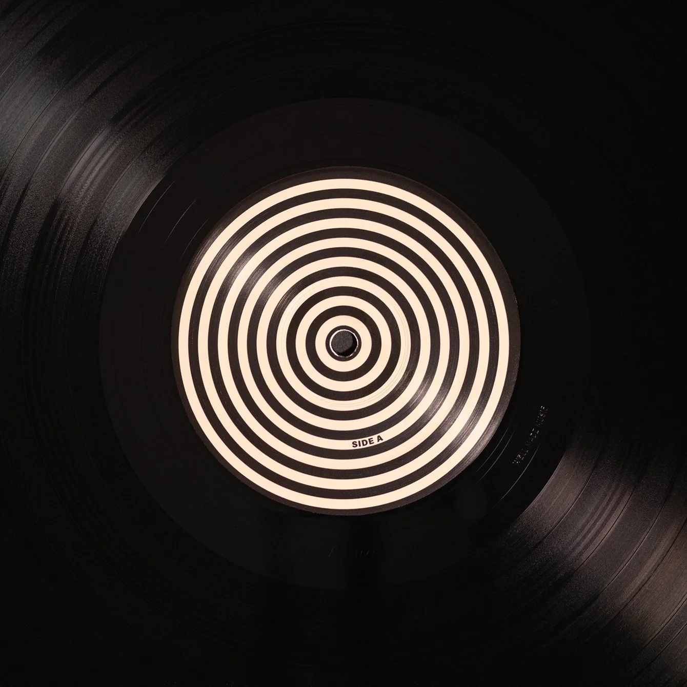 Close-up of a black vinyl record with a white concentric spiral pattern on the label, marked 'Side A'.