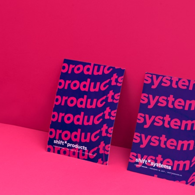Two posters with purple backgrounds and pink text, promoting 'shift + products' and 'shift + systems', placed against a pink wall and surface.