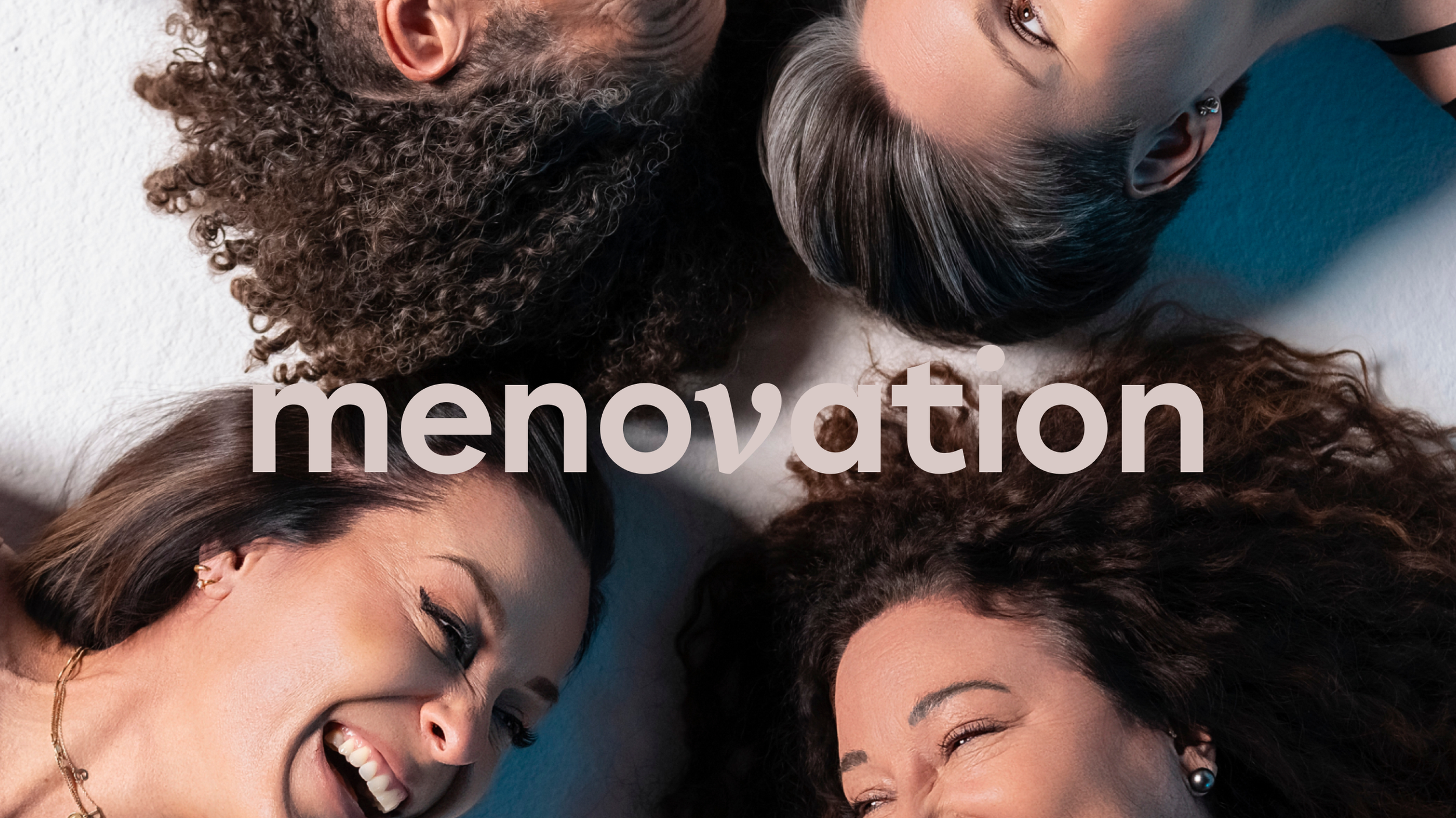 Four diverse women lying on the floor in a circle, smiling and laughing, with the word 'menvation' overlaid in the center.