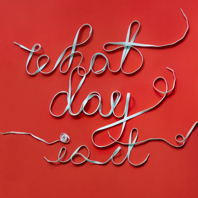 Shoelaces arranged to spell 'what day is it' on a red background.