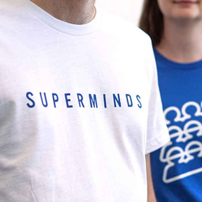 Close-up of two people wearing T-shirts, one white with 'SUPERMINDS' printed in blue lettering, and one blue with a white graphic of clouds.