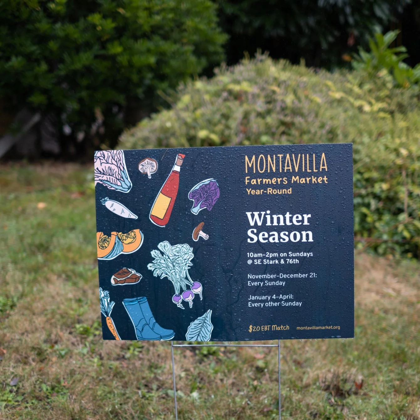 Signboard for Montavilla Farmers Market's Winter Season, held Sundays from 10 am to 2 pm at SE Stark and 76th, from November to December 21 and January 4 to April, with $20 EBT match, outdoor display with illustrations of vegetables, mushrooms, a bottle, and boots.