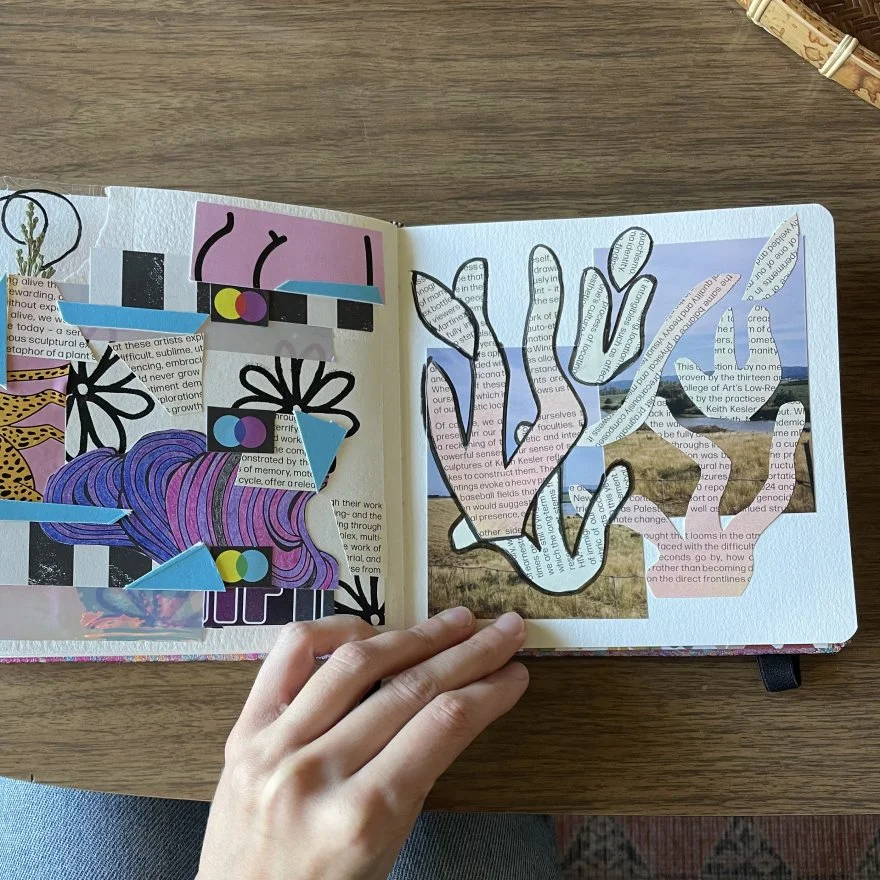 Open scrapbook with cut-out and collage art, including flowers, abstract shapes, text, and photos, on a wooden table.