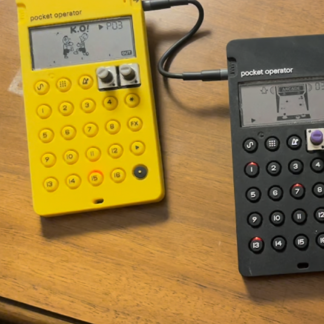 Yellow and black pocket calculators connected by a cable on a wooden surface.
