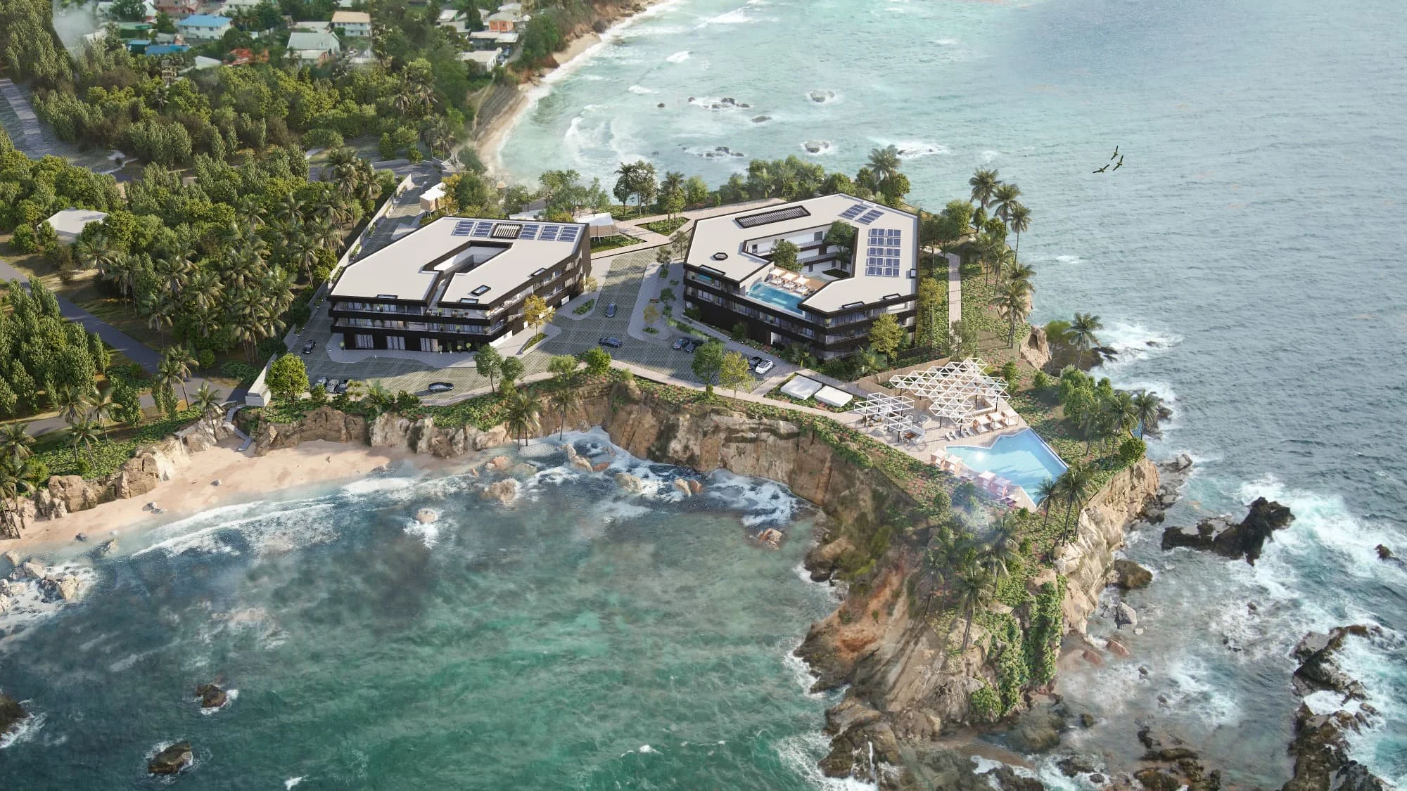 Aerial view of a luxurious coastal resort with two modern buildings on a rocky peninsula, a swimming pool, palm trees, and a beach with waves crashing below.