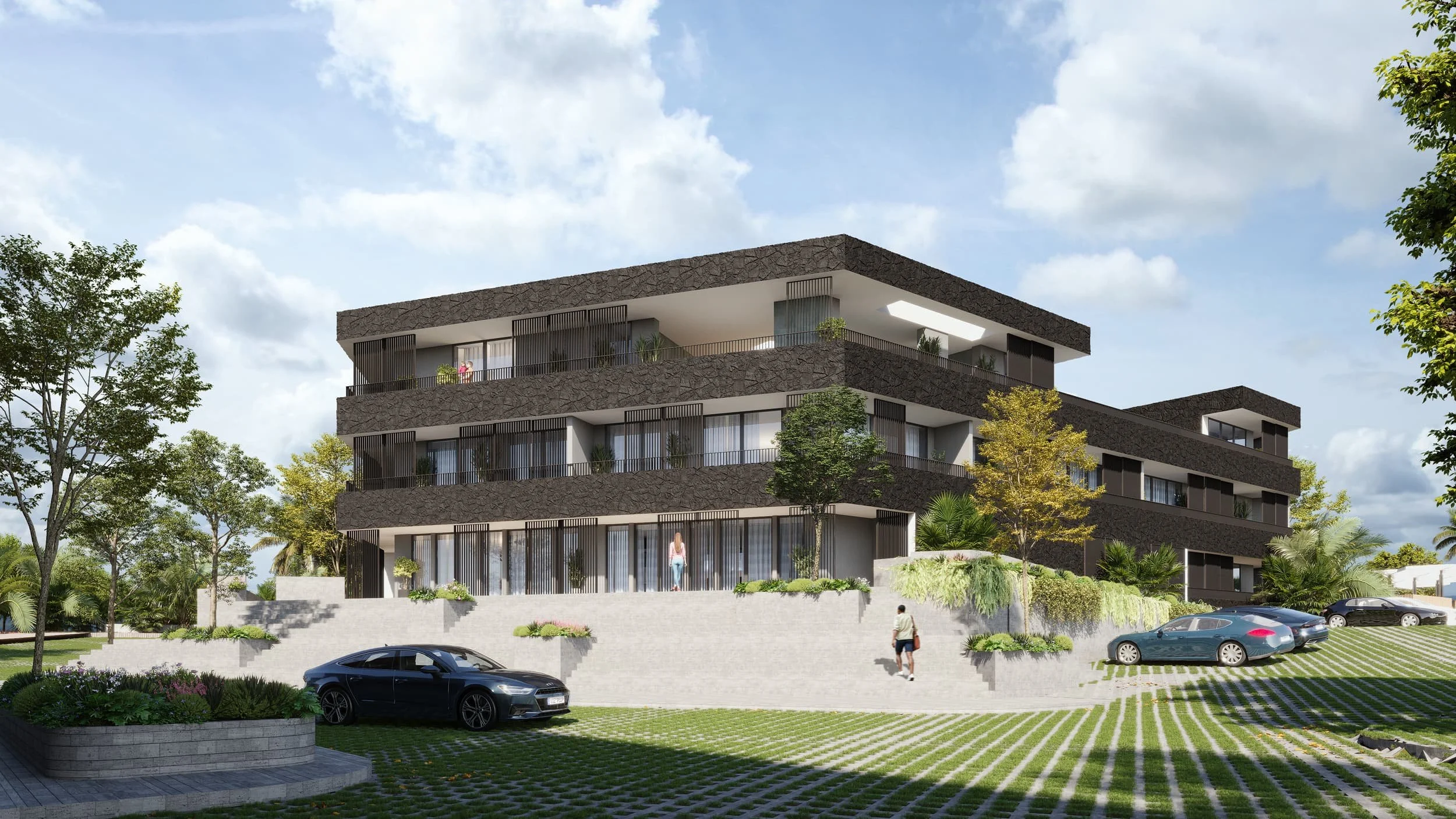 Modern three-story apartment building with balconies and greenery on Plymouth Peninsula, Tobago; cars parked under a partly cloudy sky.