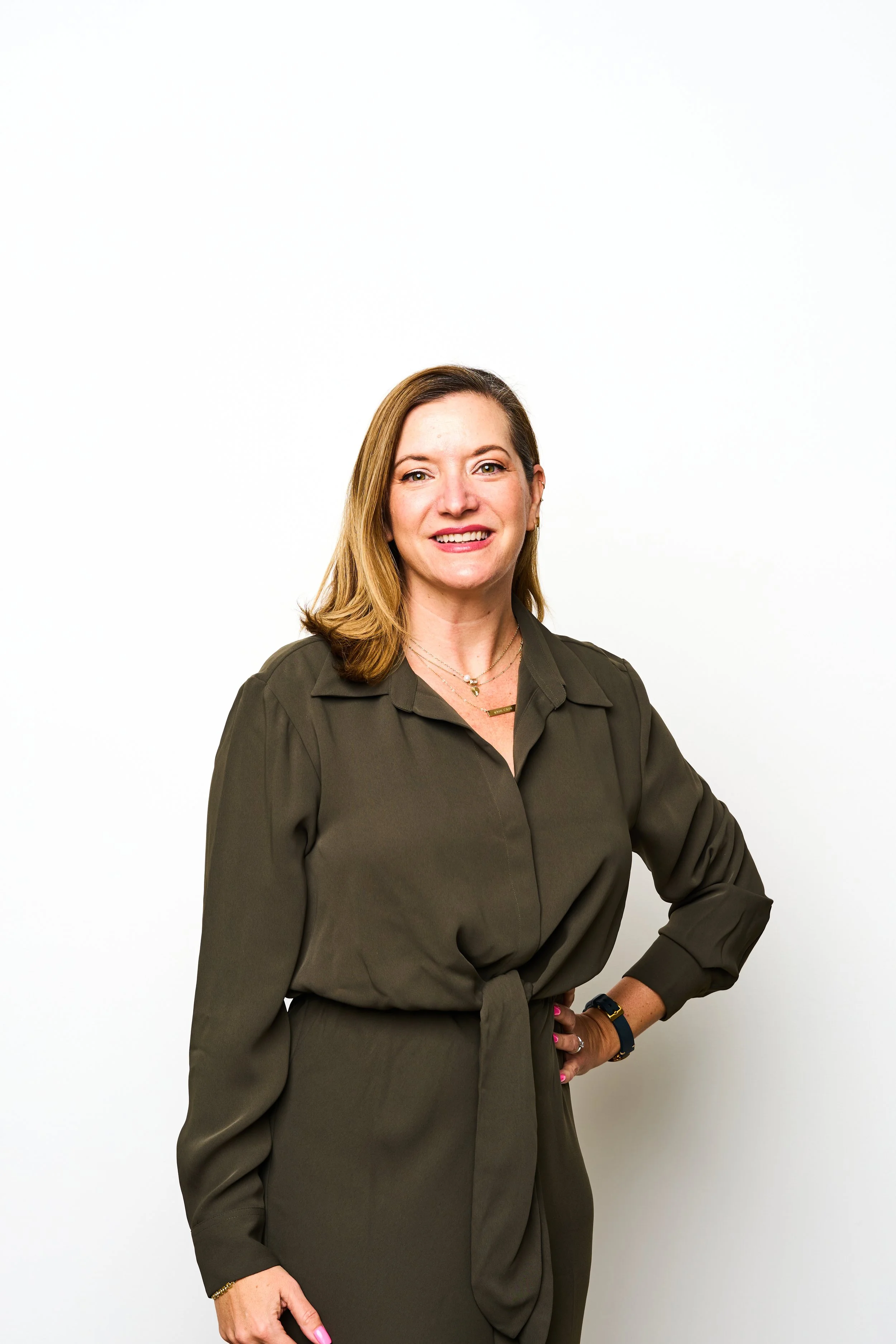 Smiling woman in green dress against white background.
