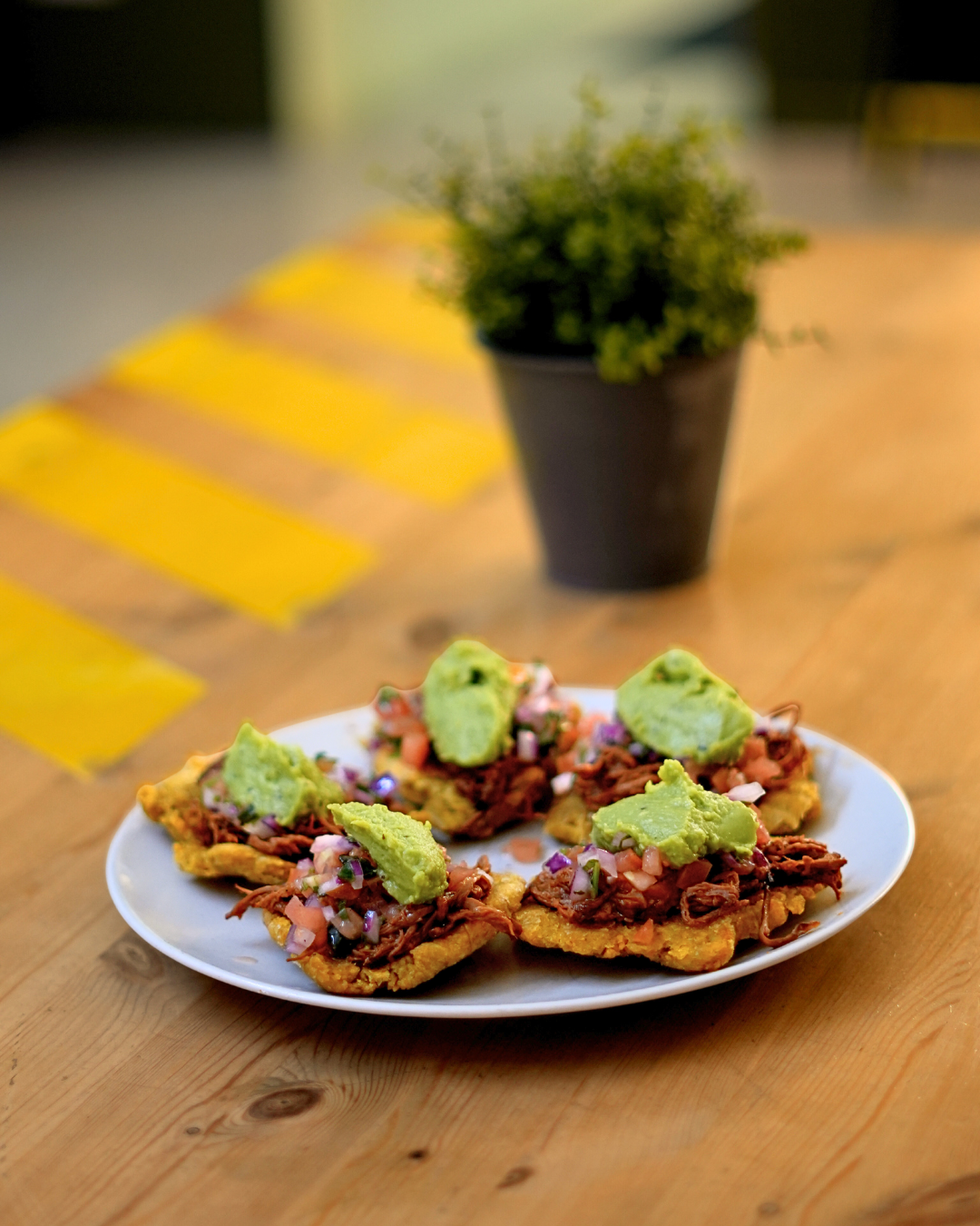 Plato de patacones con carne mechada, guacamole y pico de gallo