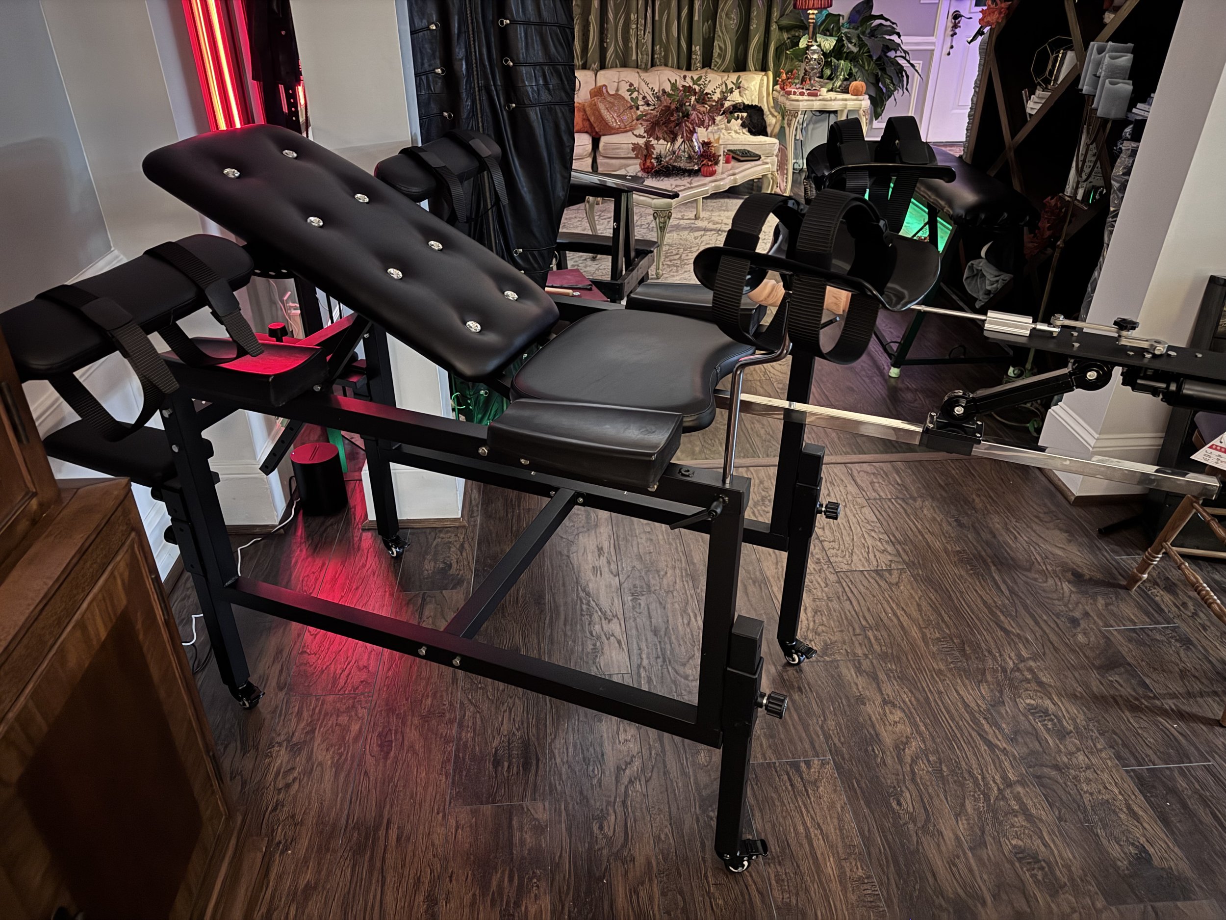 Medical or chiropractic adjustment table in a room with hardwood floors, black leather upholstery, and various decorative items in the background.
