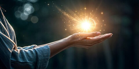 Hand holding glowing light or energy source in a natural outdoor setting with sunlight and bokeh background.