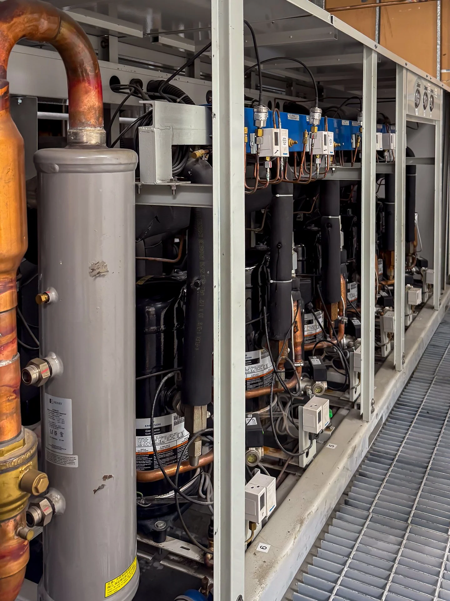 Componentes del sistema de refrigeración, incluyendo compresores, tuberías de cobre y válvulas en una unidad de aire acondicionado industrial.