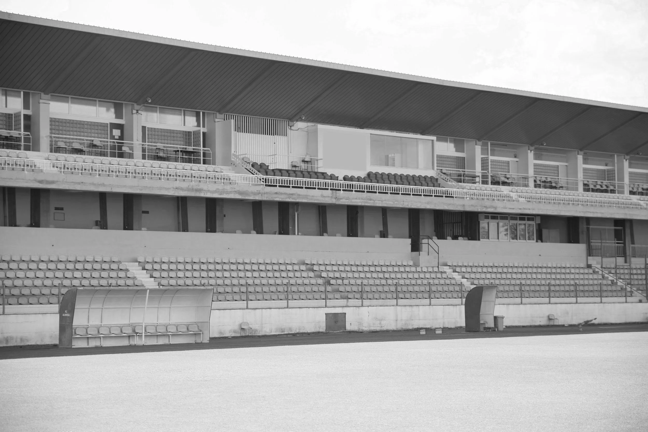 Imagen en blanco y negro de un estadio vacío, con bancos para espectadores y un campo de juego.