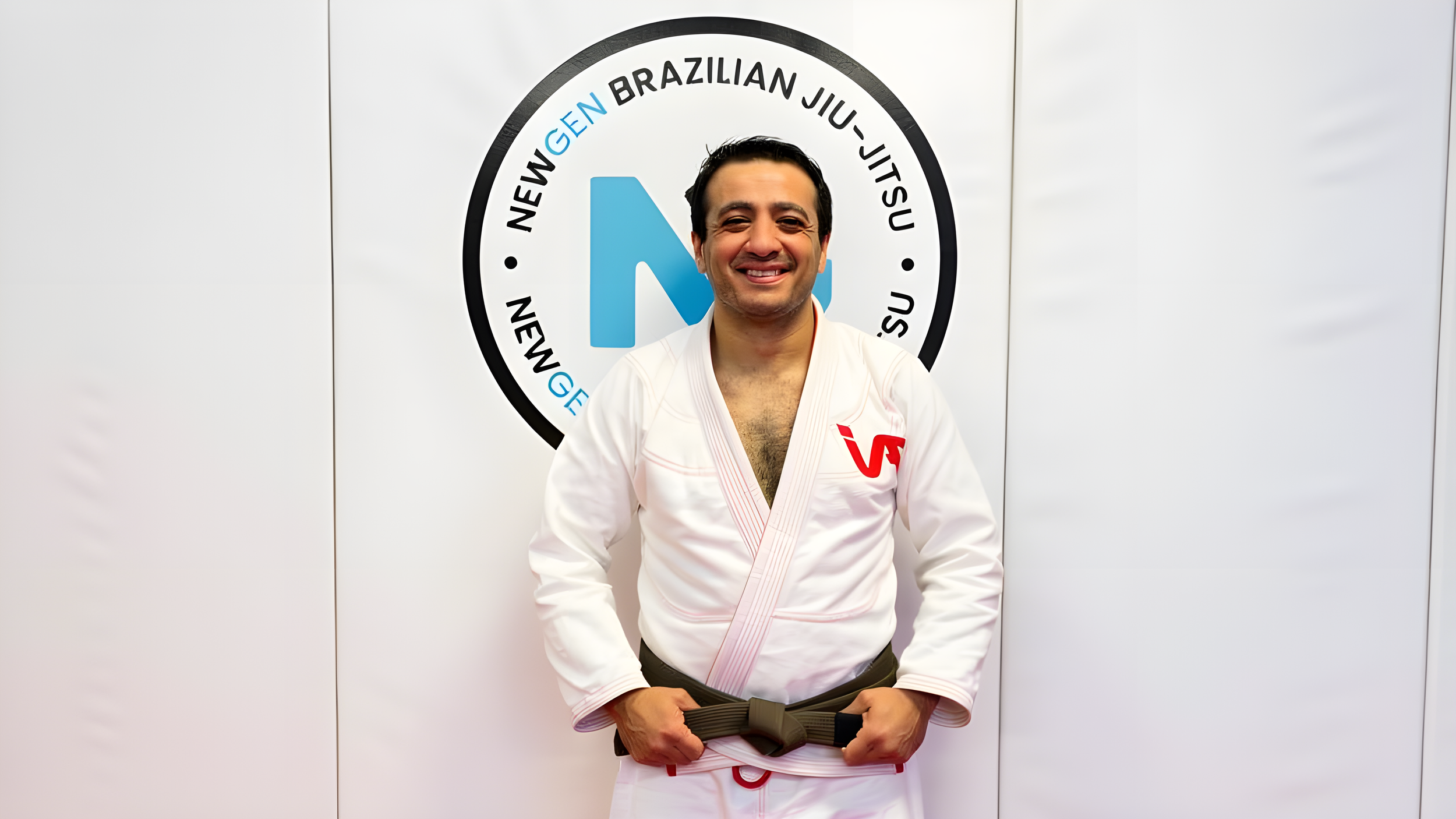 Coach Sertac Peduk, founder of NewGen BJJ, in a white gi at the NewGen Brazilian Jiu-Jitsu gym