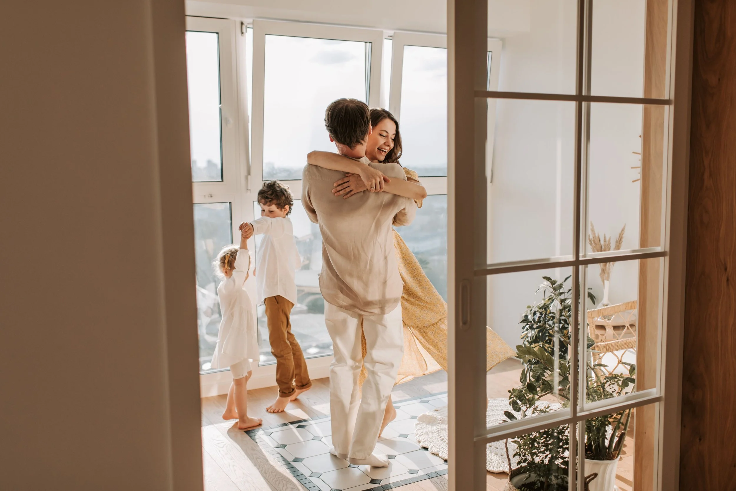 Christian family worshipping together in their living room, dancing, laughing, and enjoying joyful time together while worship music plays, creating a faith-filled and Christ-centered home atmosphere.