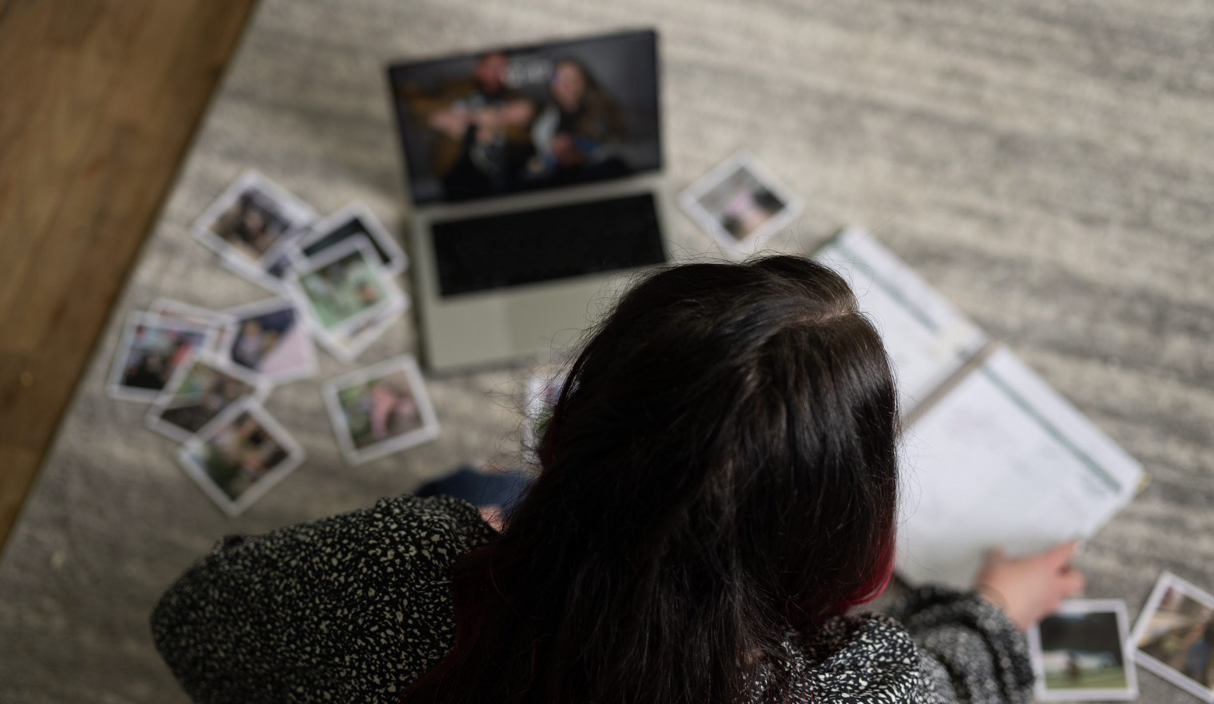 Woman working on blog planning at a computer with printed photos laid out for content planning