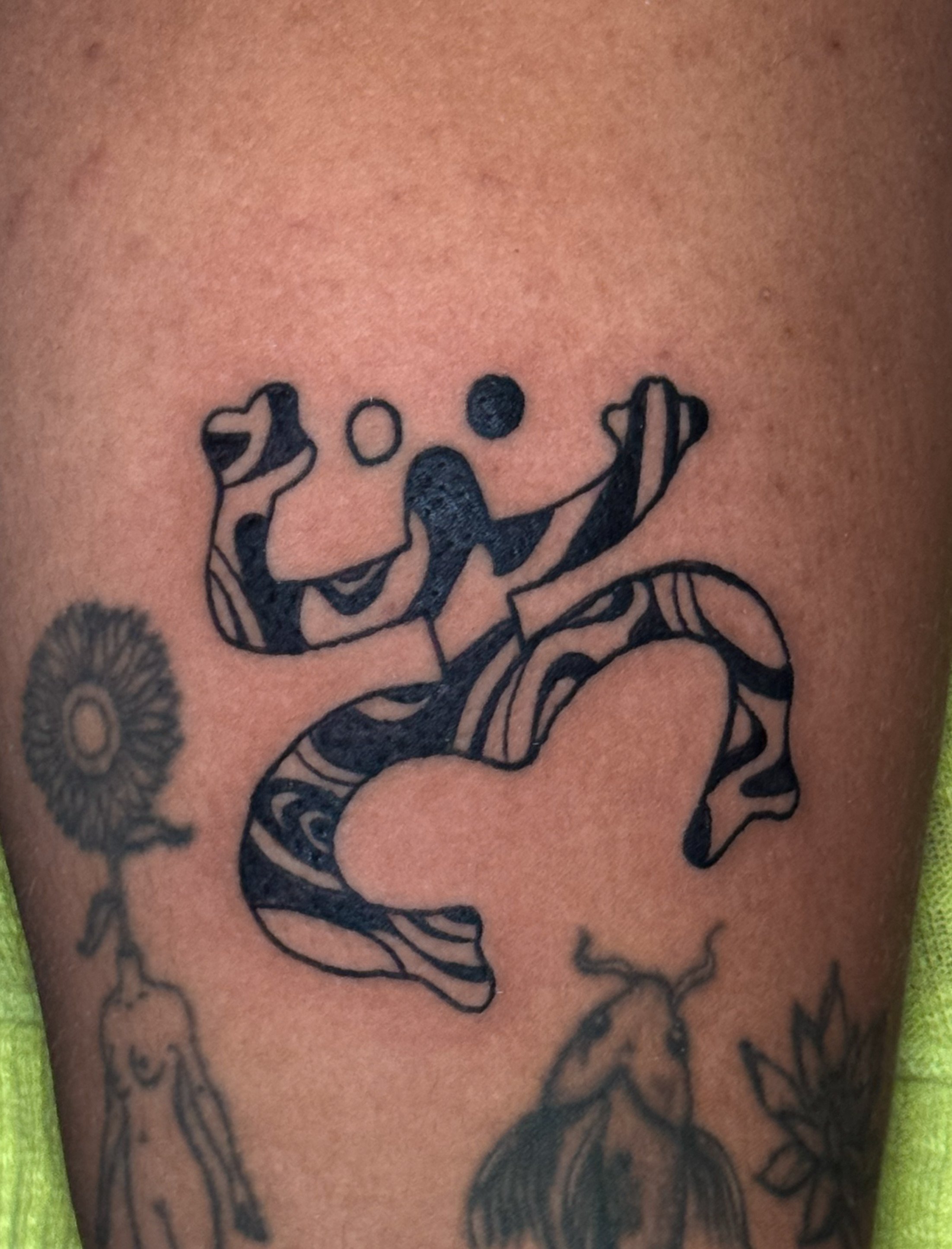 Close-up of a tattoo on skin featuring a stylized human figure playing basketball, with additional floral and line designs.