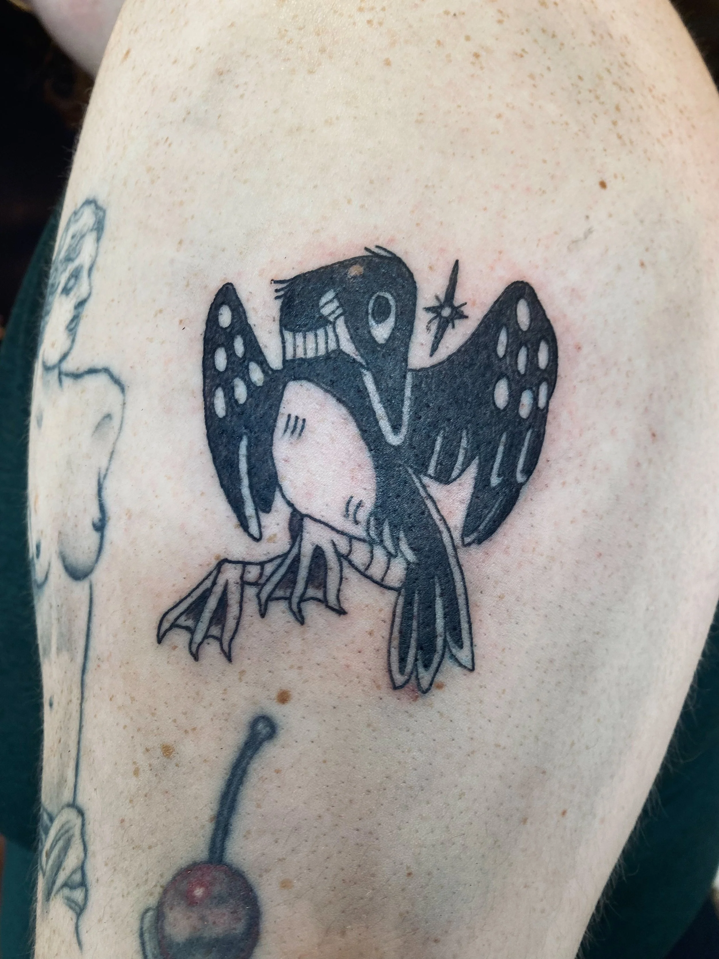 A tattoo of a bird, possibly a swallow, with detailed wings and a long tail, on light skin.