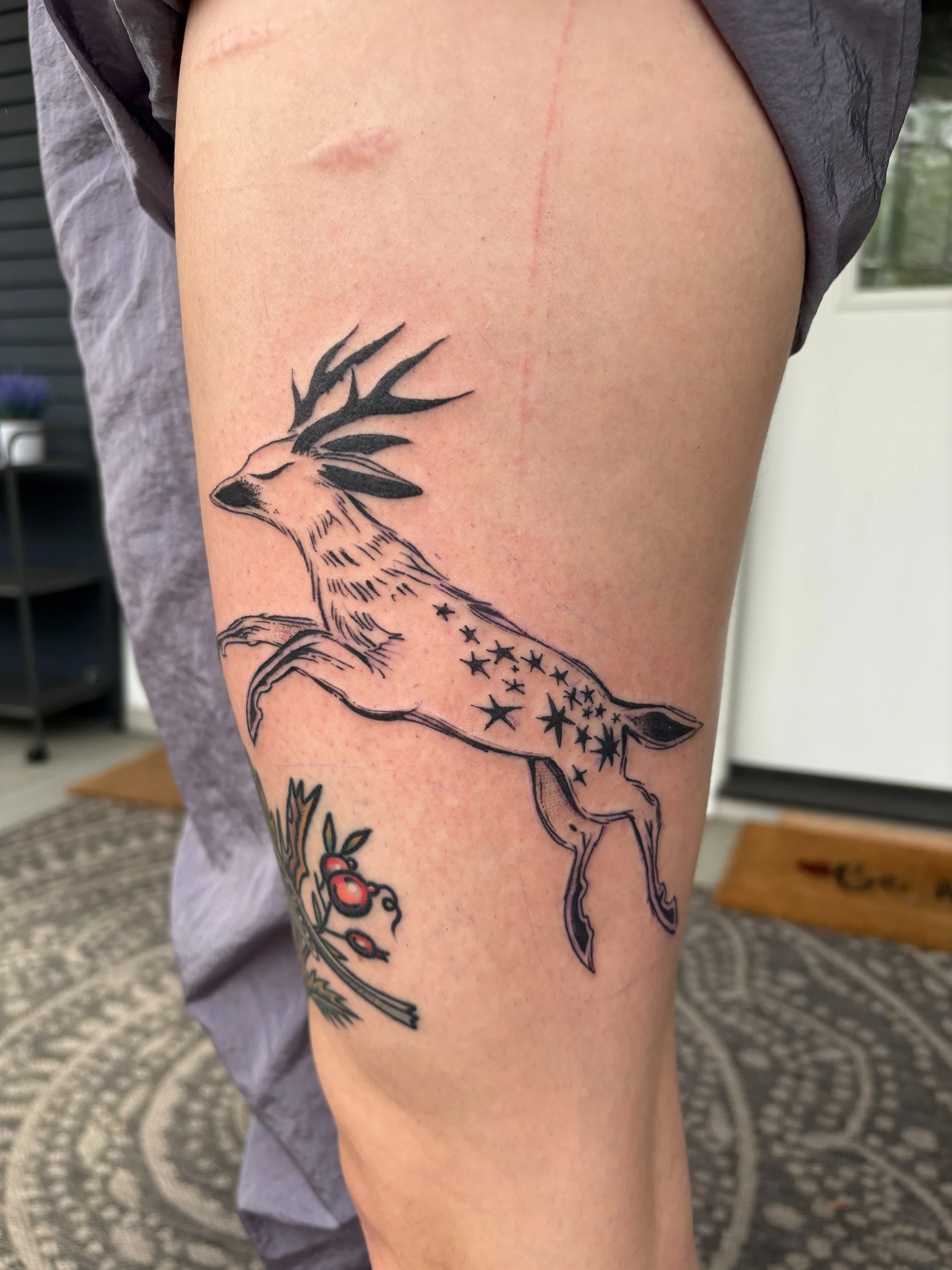 Tattoo of a stylized deer with black and orange markings, standing on a person's thigh.