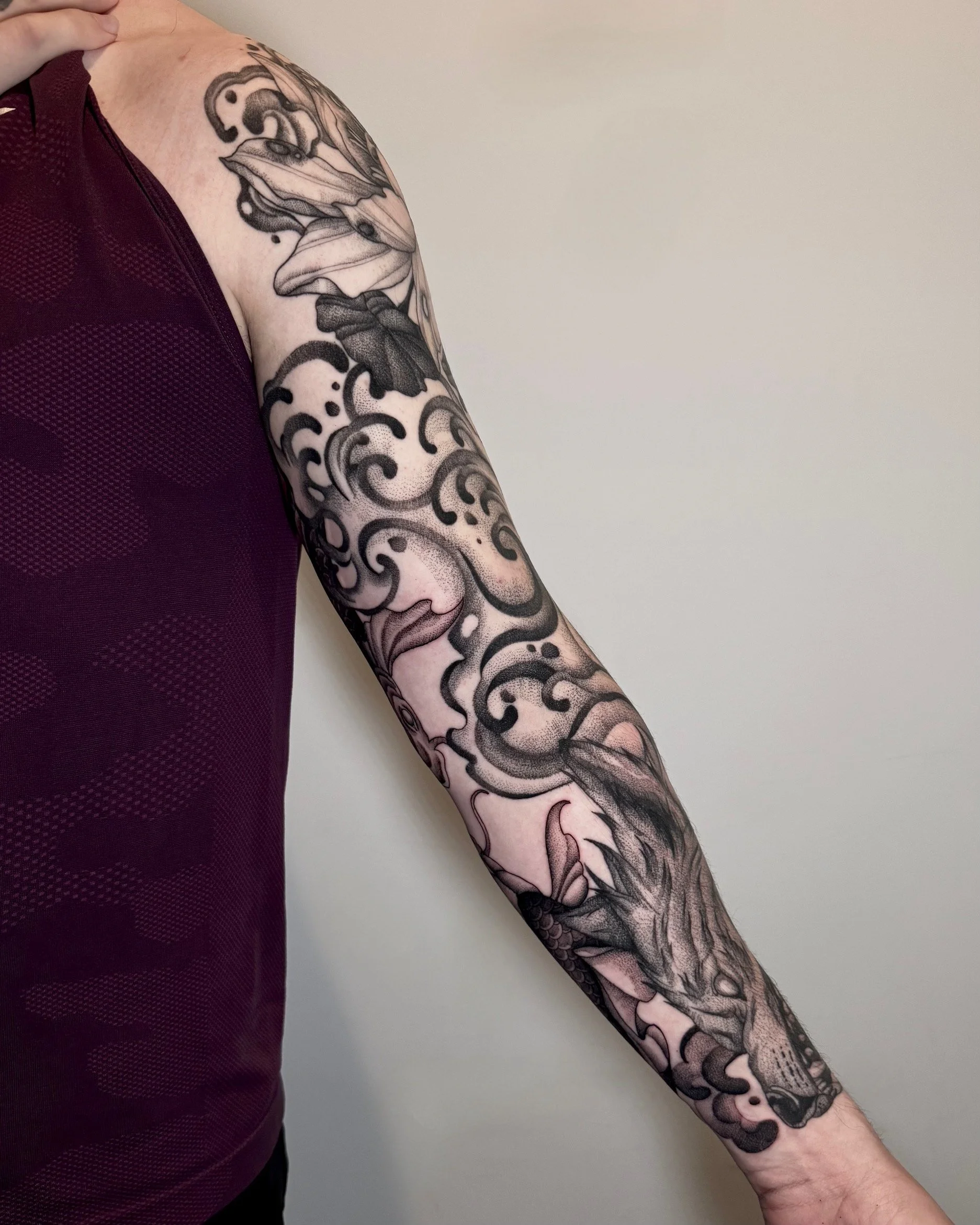Tattoo sleeve on person's arm featuring a mountain lion with a detailed face, surrounded by swirling cloud patterns and floral elements.