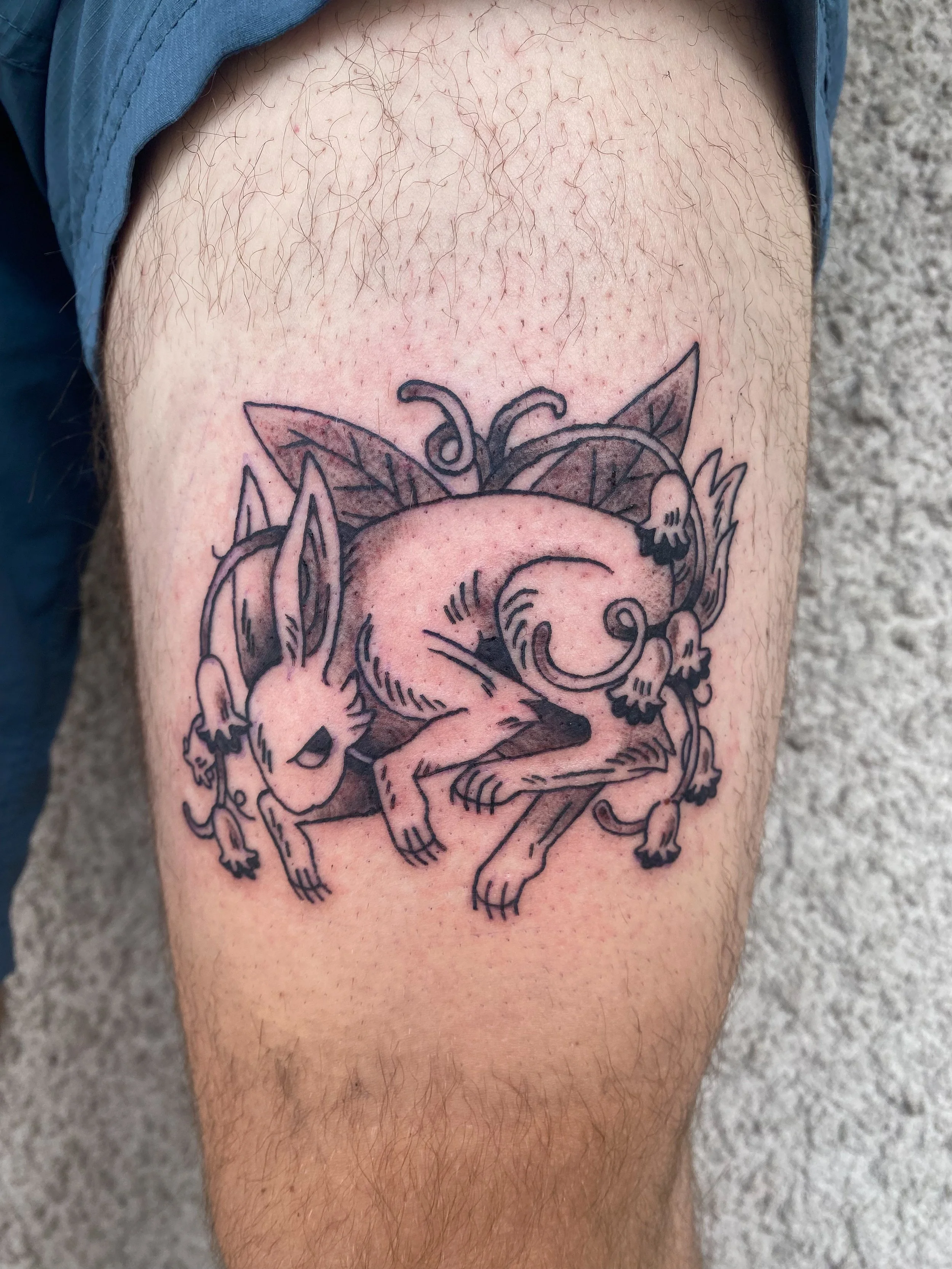 A tattoo of a fox with flowers and leaves on a person's upper arm.
