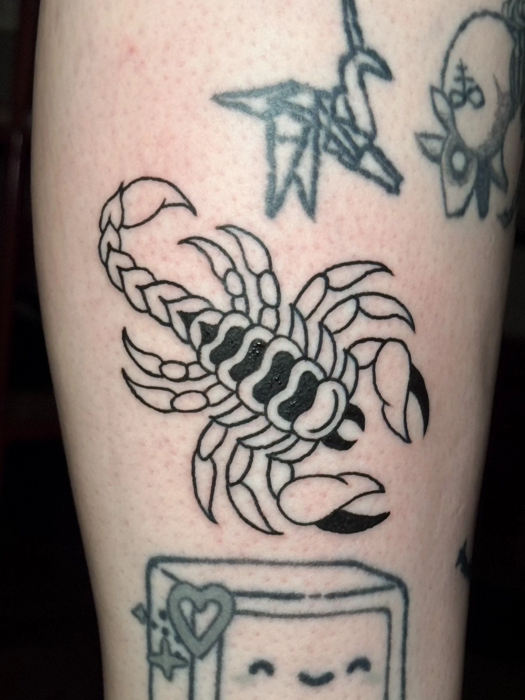 Black outline tattoo of a scorpion on skin.