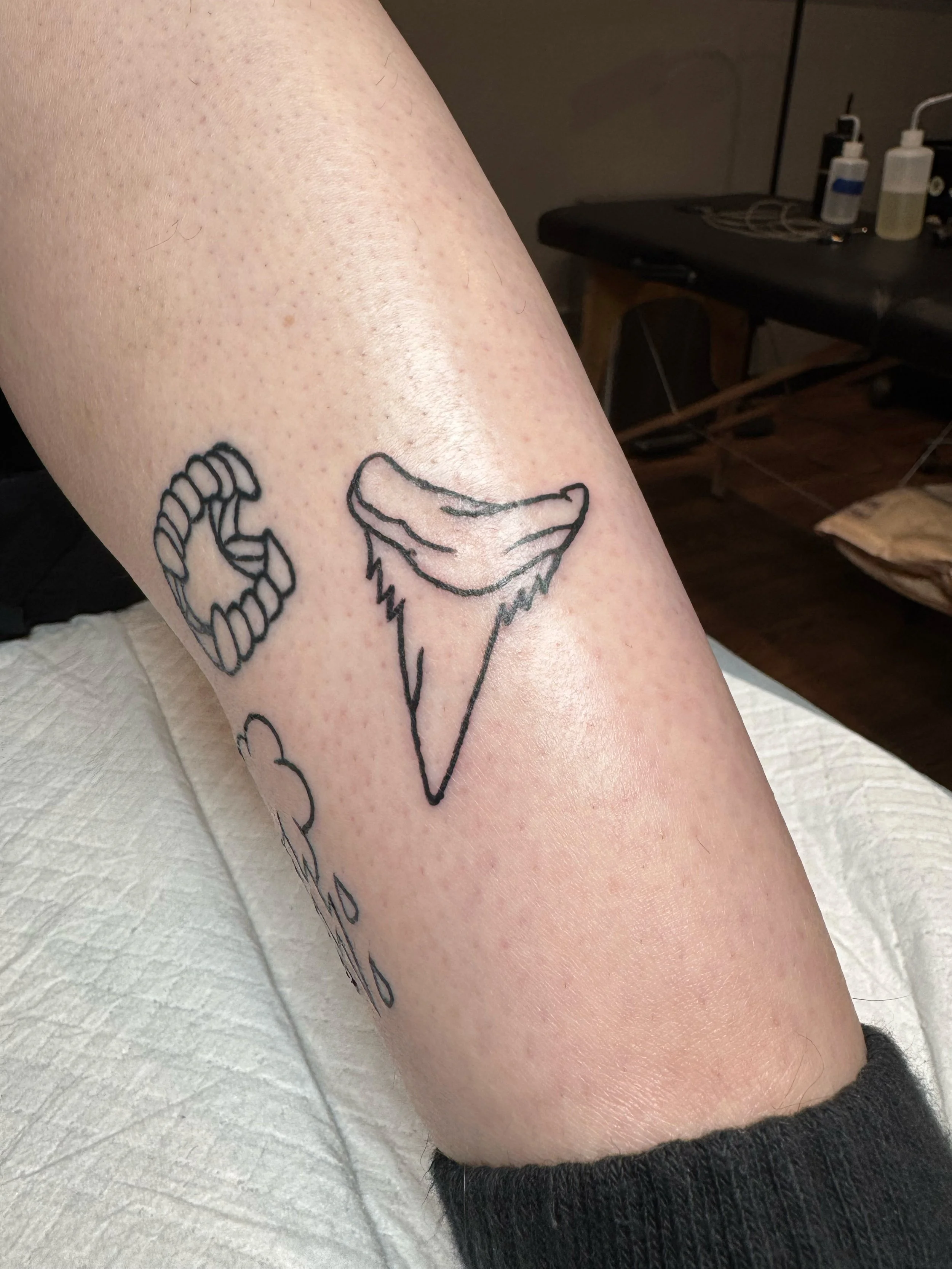 Tattoo of a stylized ice cream cone and partially visible text on a person's forearm.