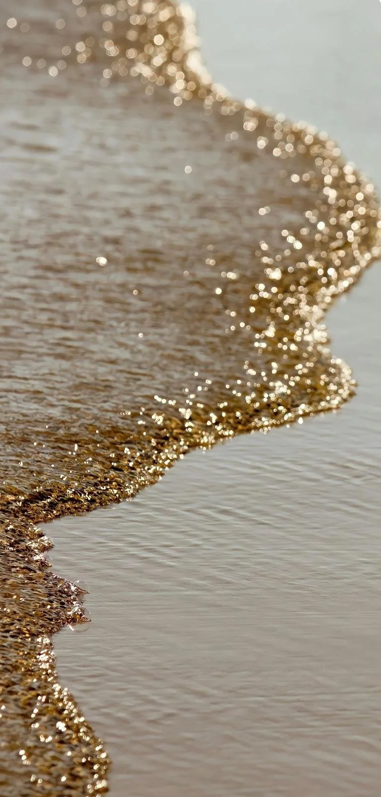 Goldene Sandkörner am Strand im Sonnenlicht