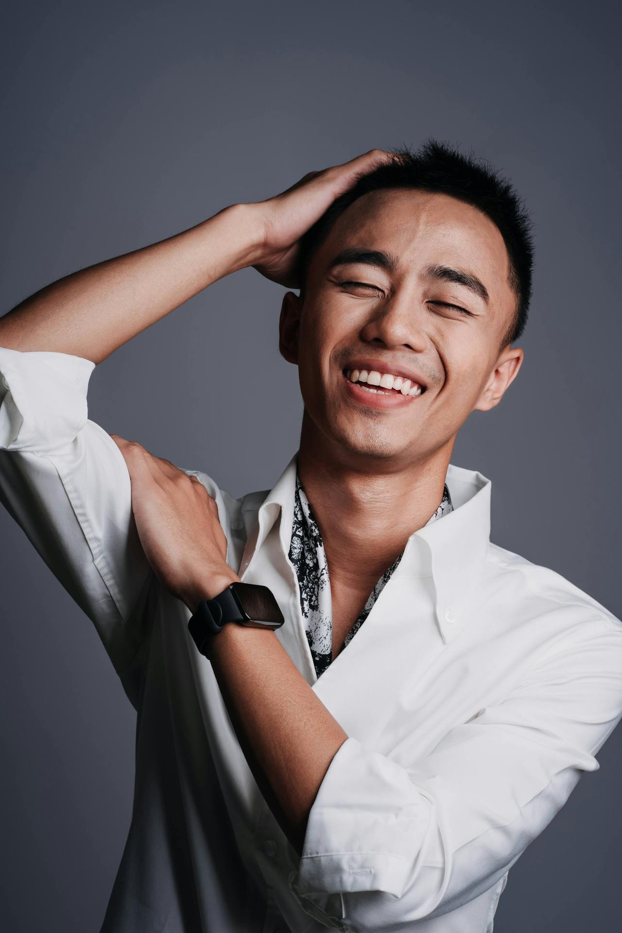 Young Asian man with a hand on his head and a smile on his face in a moment of realisation