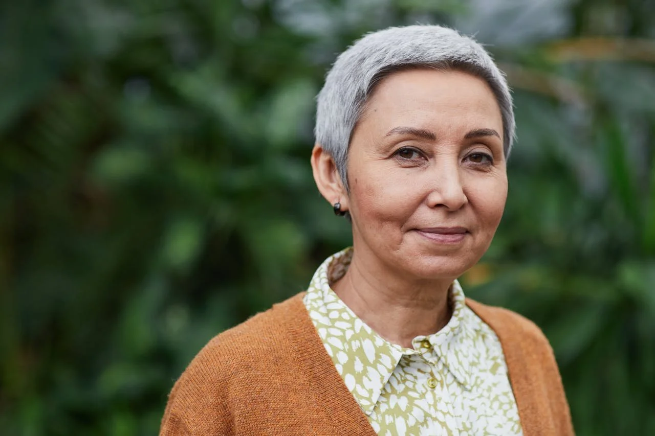 Woman in her fifties with short cropped grey hair looking relaxed and happy