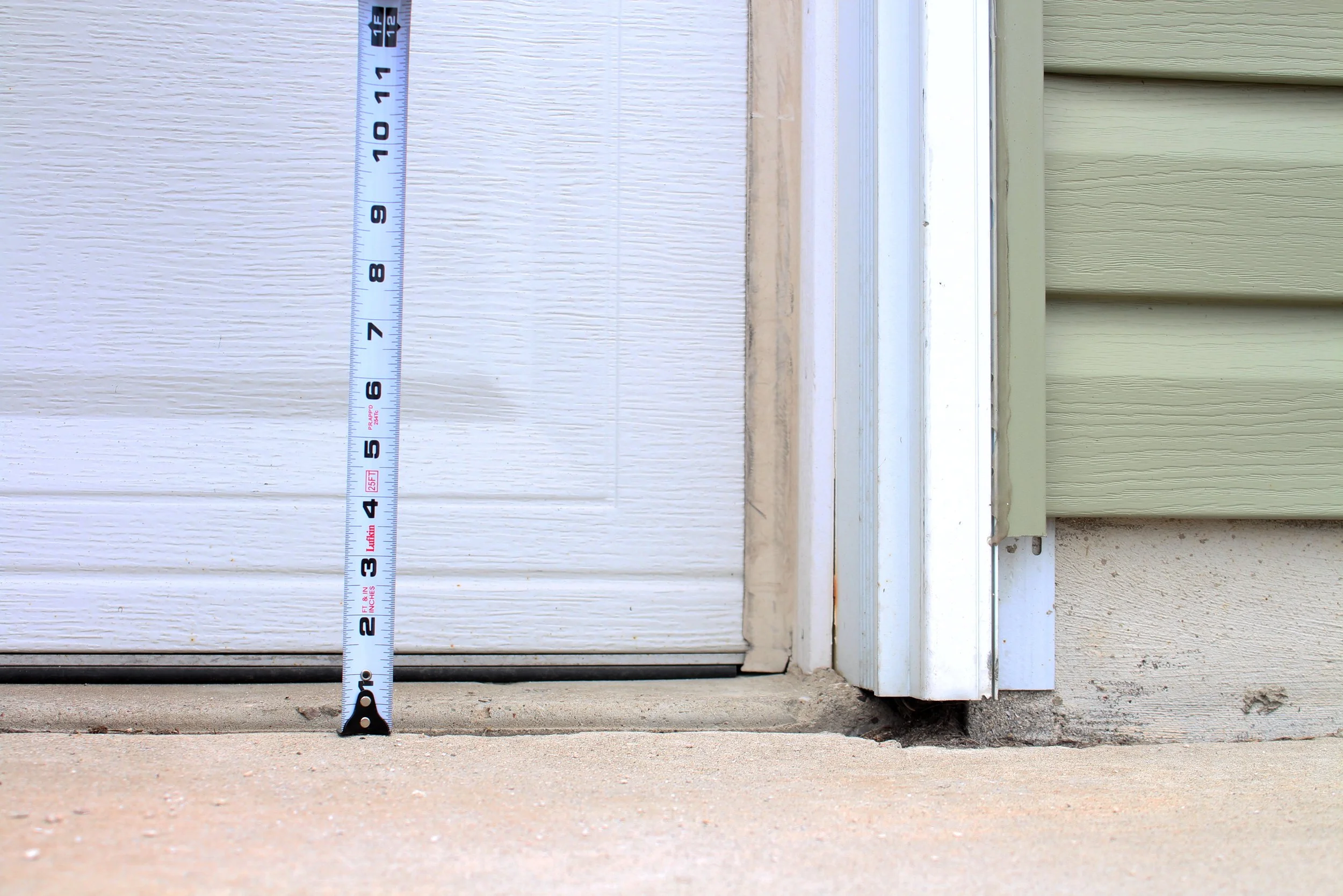 Measuring tape placed at the bottom of a garage door to measure clearance height.