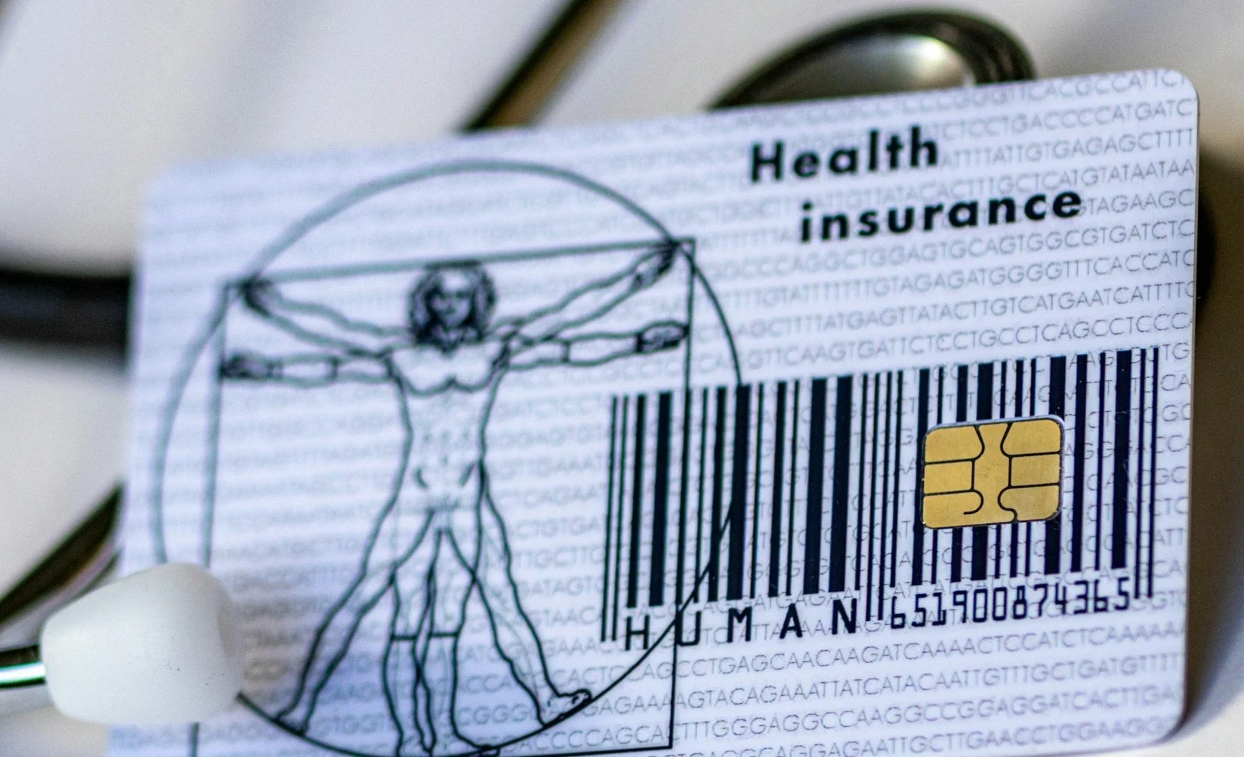 Close-up of a healthcare insurance card with Leonardo da Vinci's Vitruvian Man sketch and a barcode.