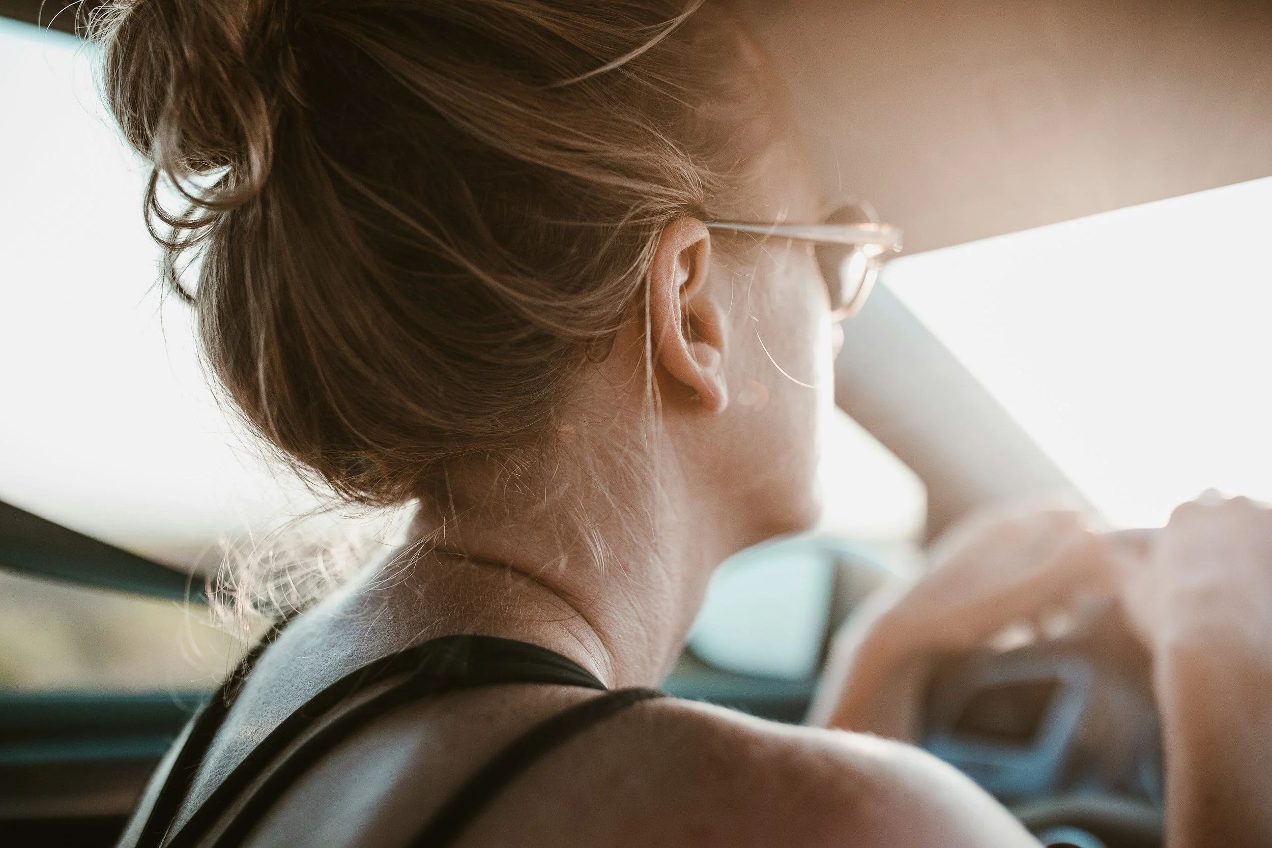 Woman sitting in a car with her hands on the steering wheel, calm and focused